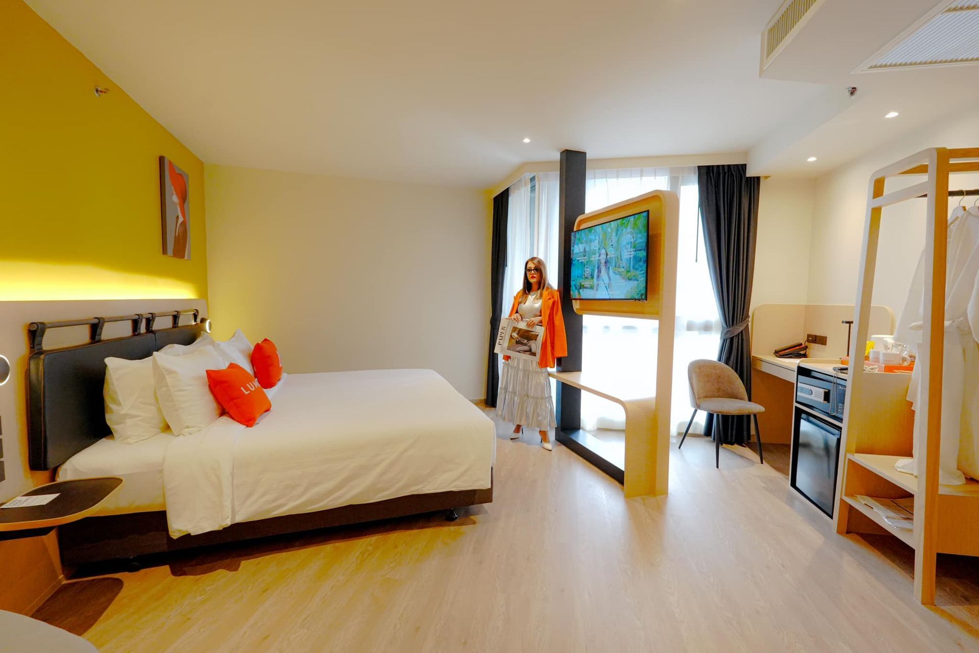 A woman is standing in a hotel room next to a bed.