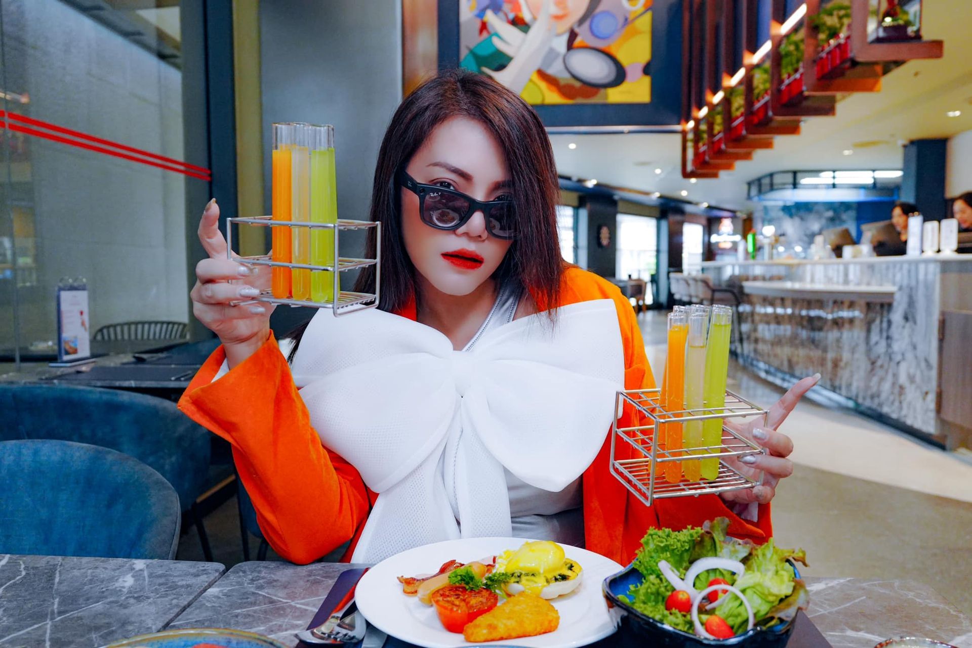 A woman is sitting at a table with a plate of food and drinks.