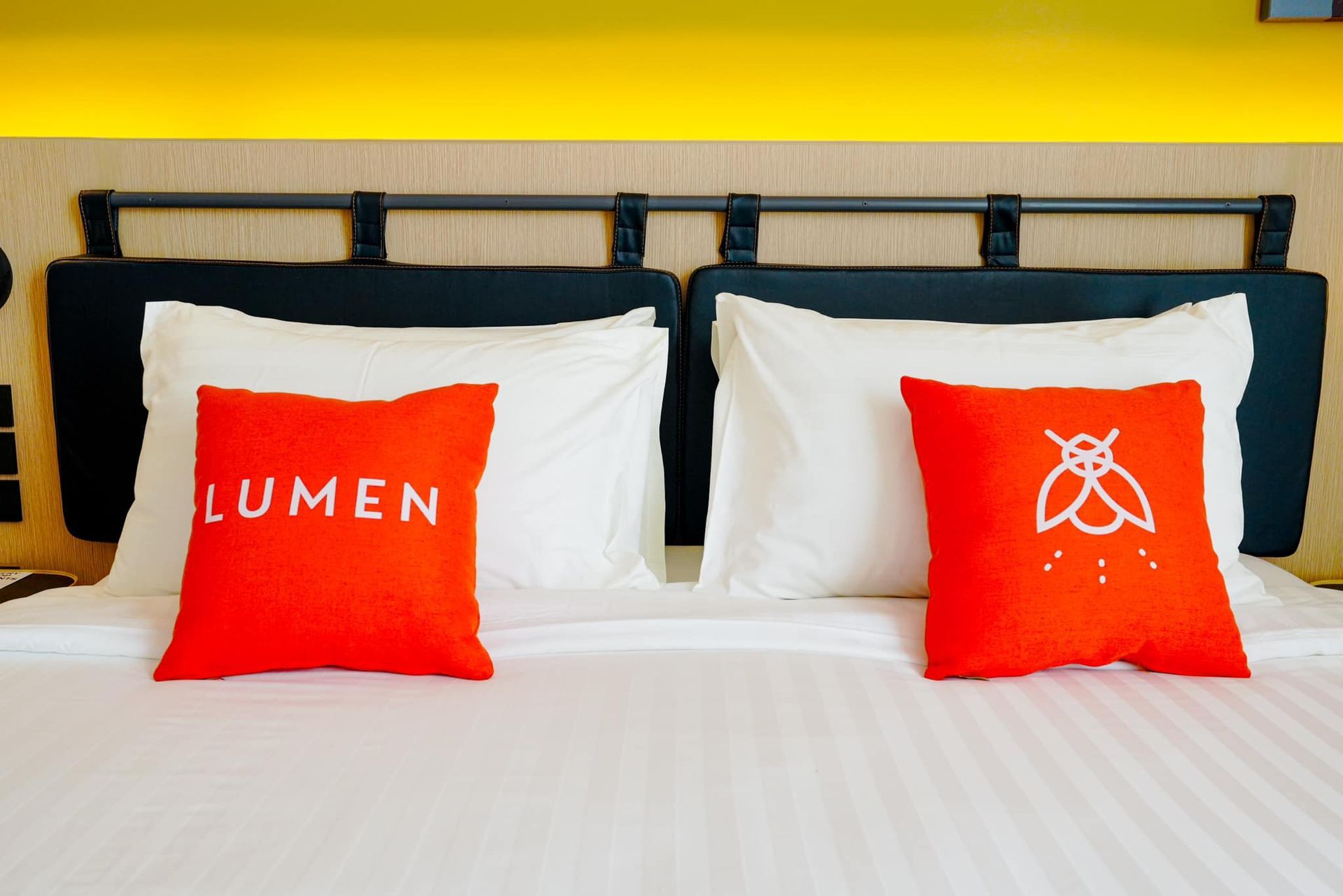 A bed with a red pillow that says lumen on it