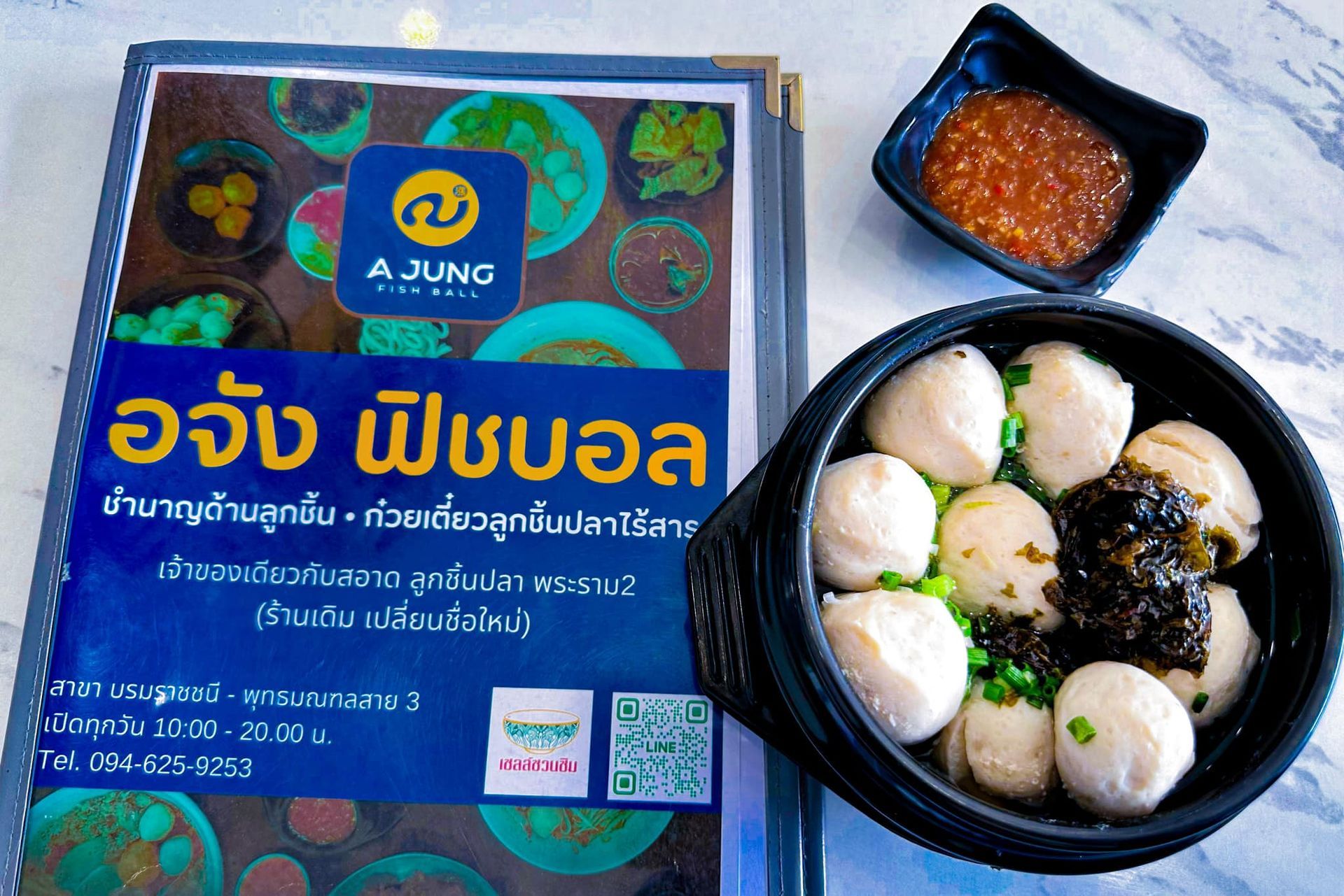 A bowl of meatballs next to a menu for ajung