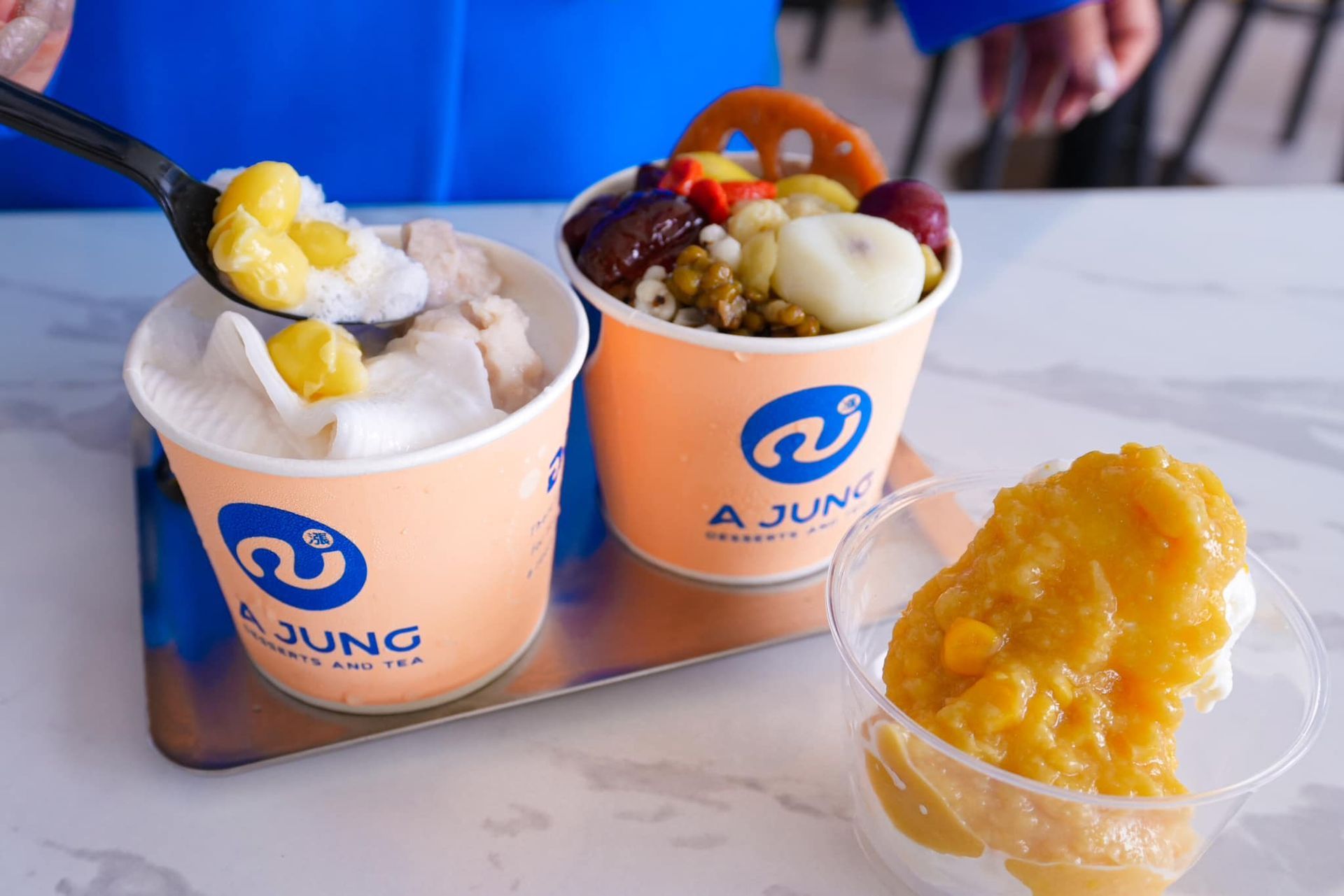 A person is eating ice cream from two cups on a table.