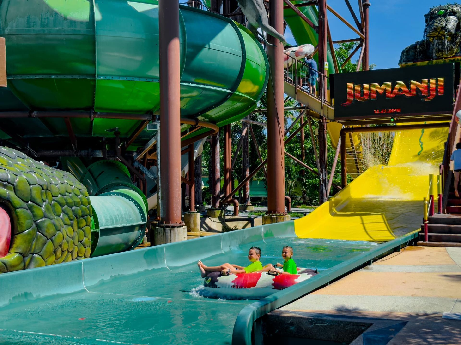 Two people are riding tubes down a water slide at a water park.