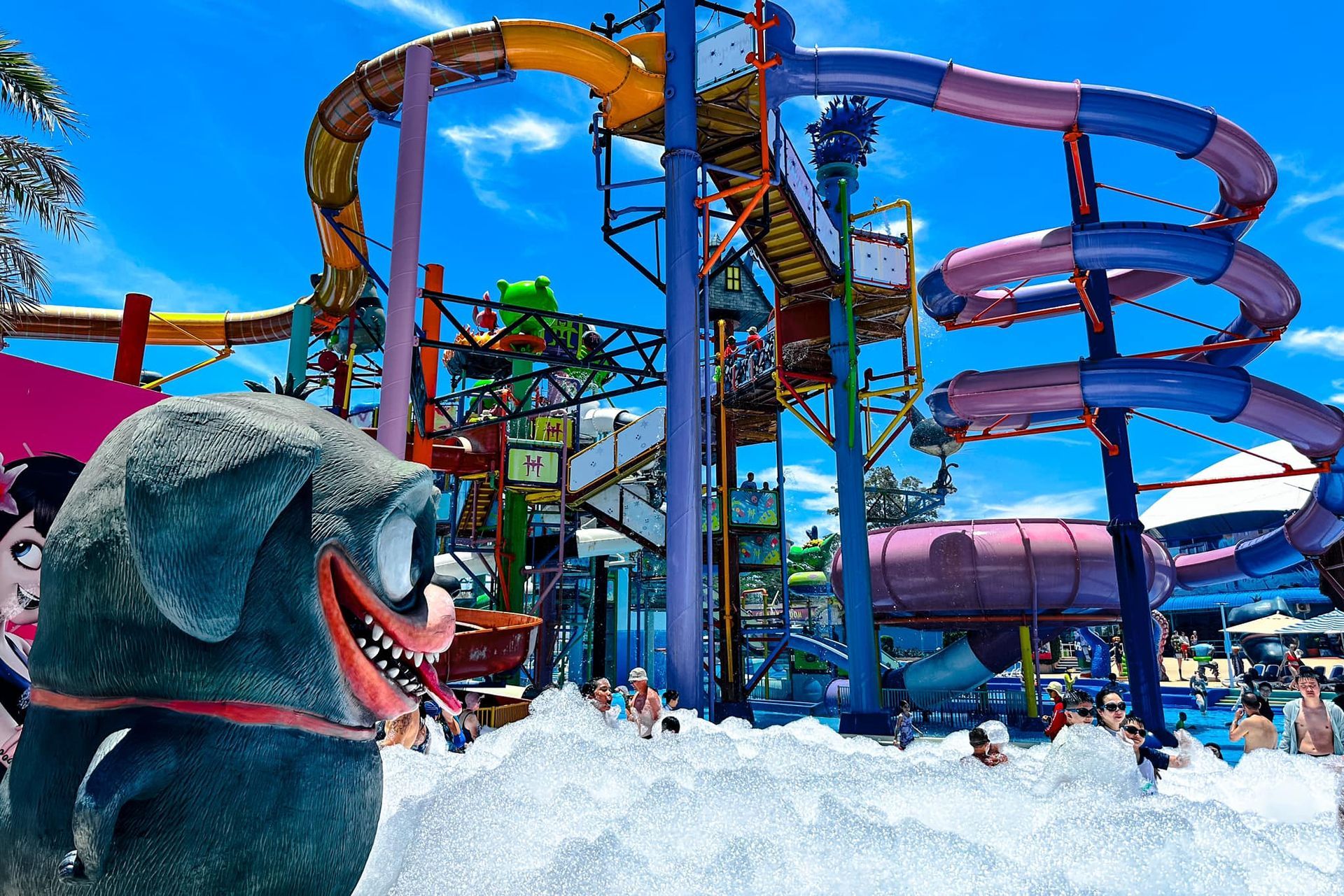 A stuffed animal is standing in front of a water slide at a water park.