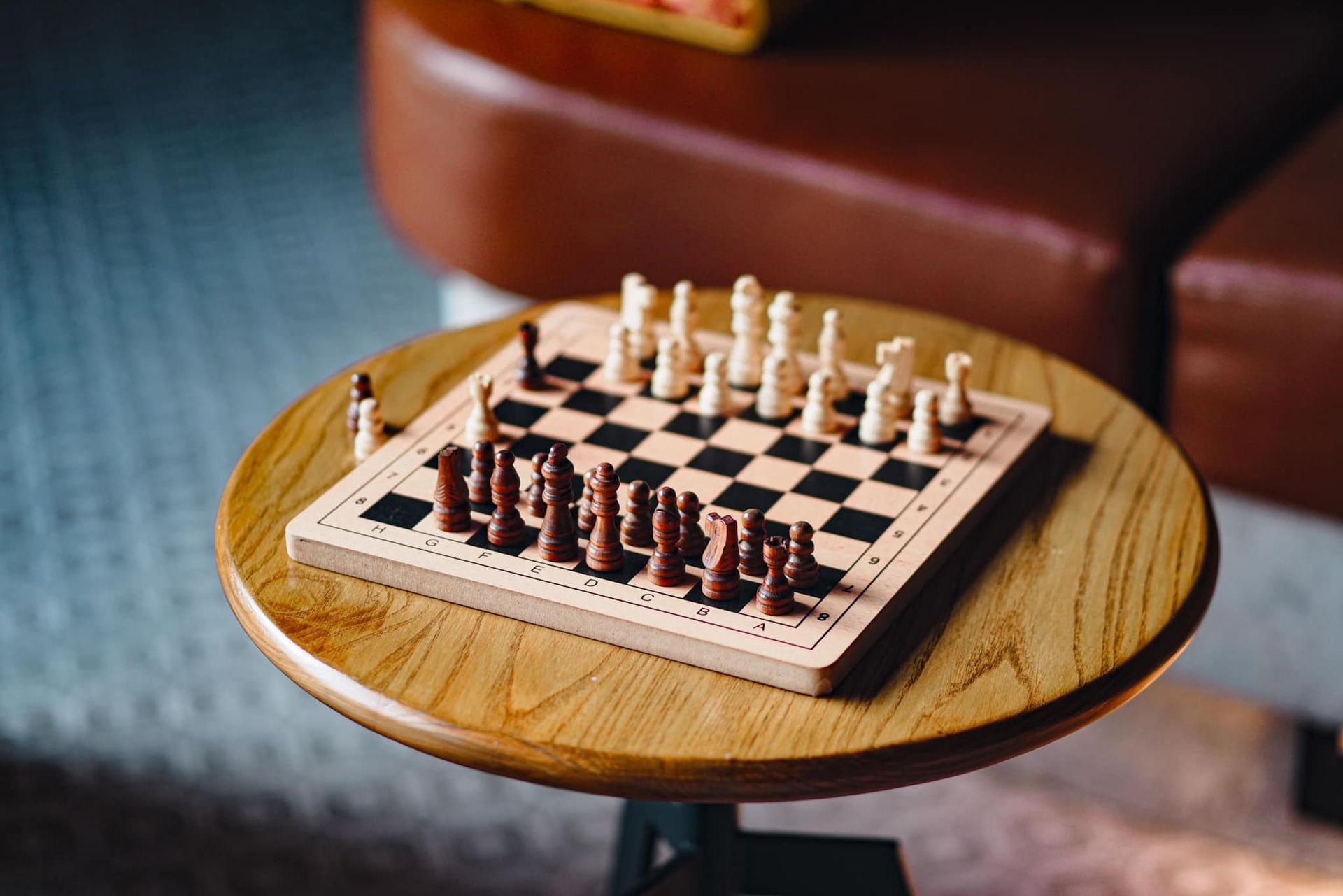 A wooden chess board with chess pieces on a wooden table.
