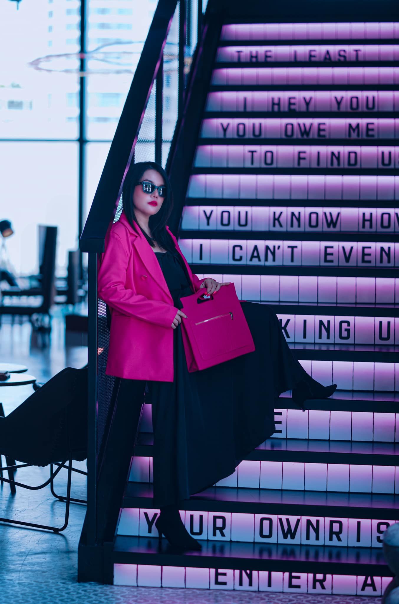 A woman in a pink jacket is standing on a set of stairs in Moxy Bangkok Ratchaprasong hotel.
