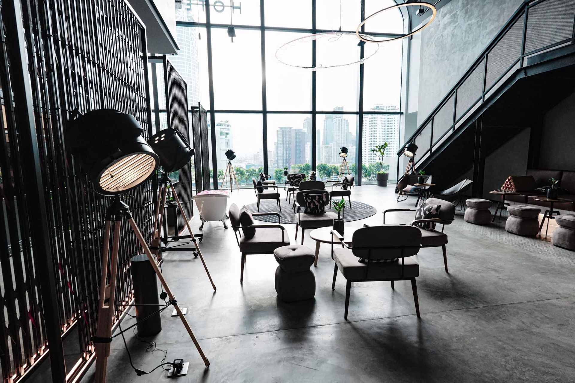 A living room with a lot of furniture and a staircase in Moxy Bangkok Ratchaprasong hotel..