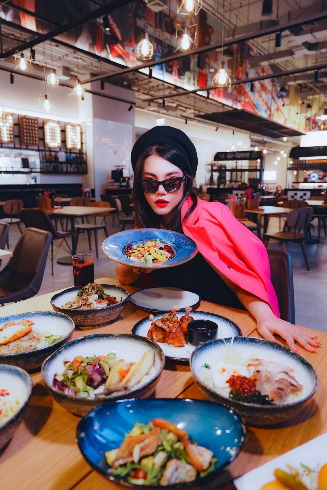 A woman is sitting at a table in a restaurant holding a plate of food.