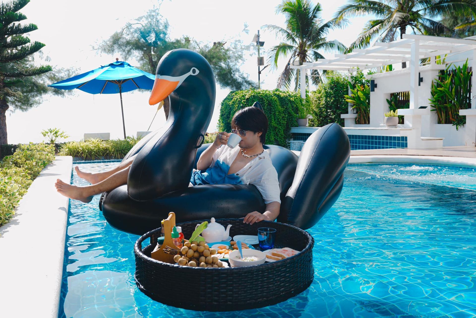 A man is sitting on an inflatable swan in a swimming pool.
