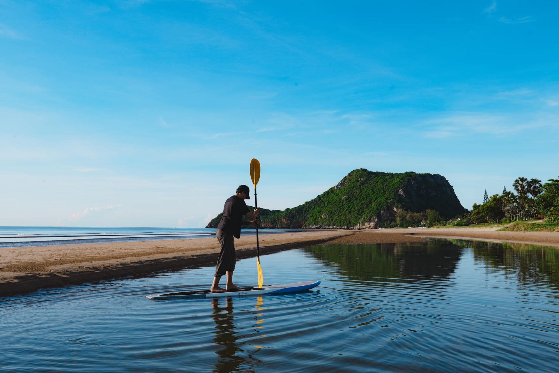A man is standing on a paddle board in the water.