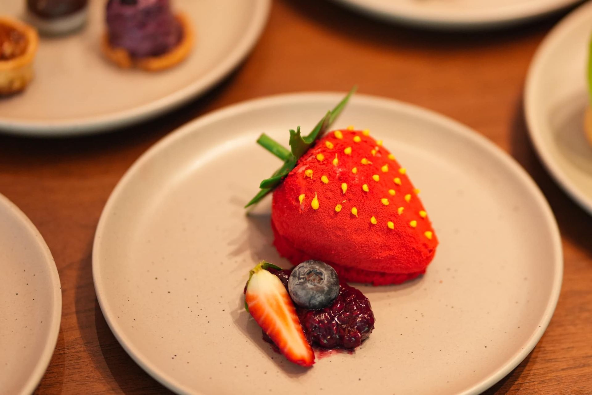 A white plate topped with a strawberry and blueberries