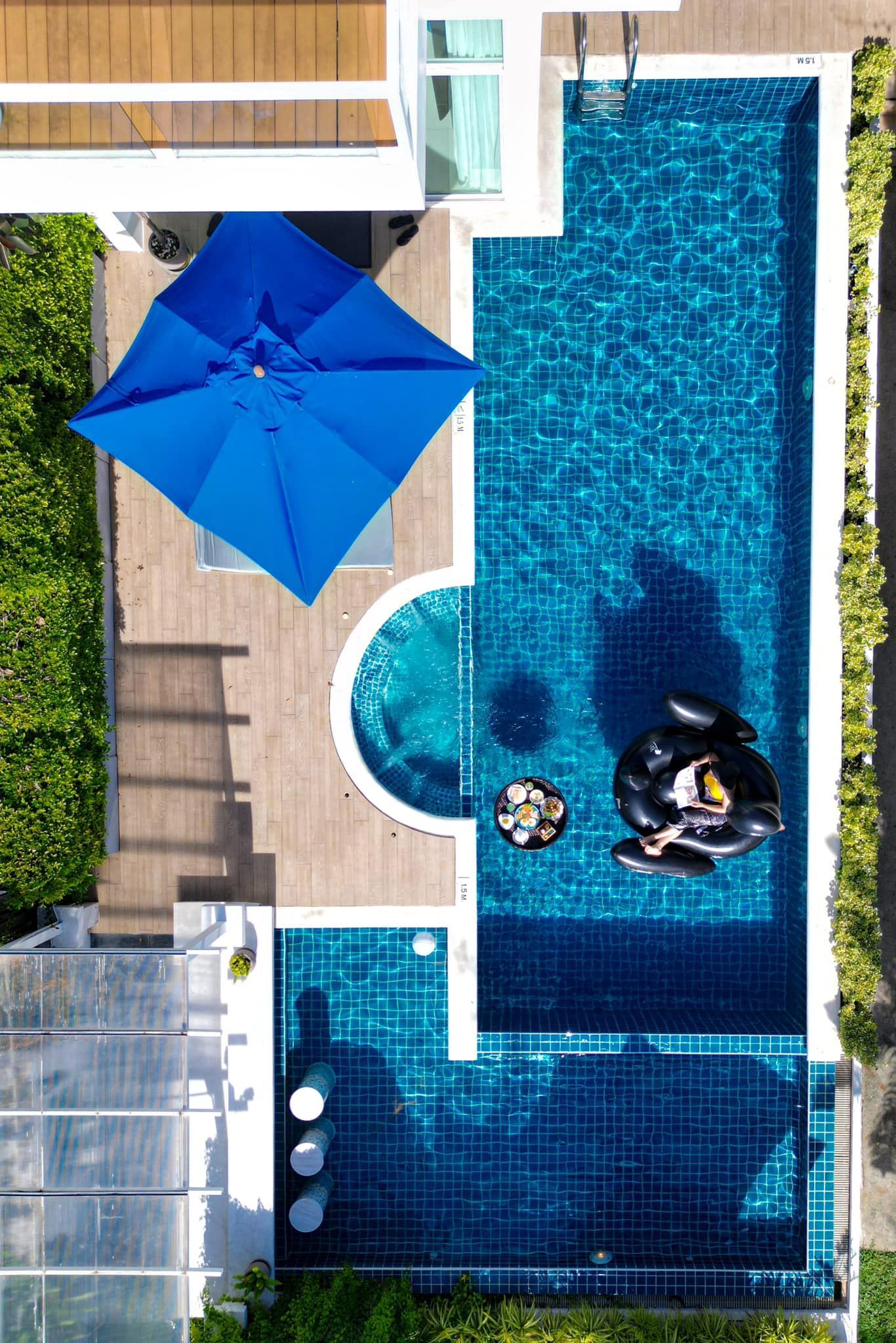 An aerial view of a swimming pool with a blue umbrella
