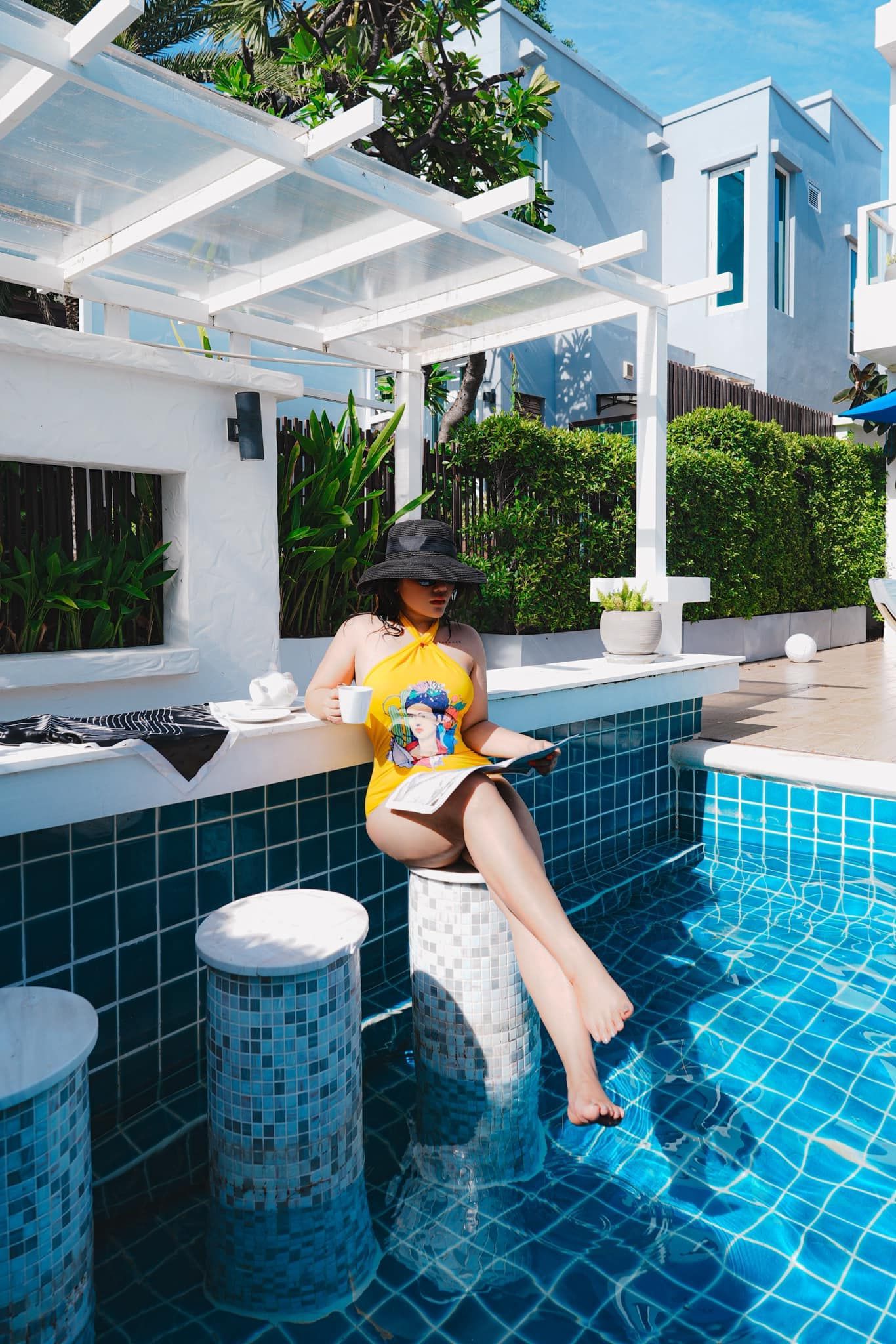 Meow is sitting at a bar next to a swimming pool.