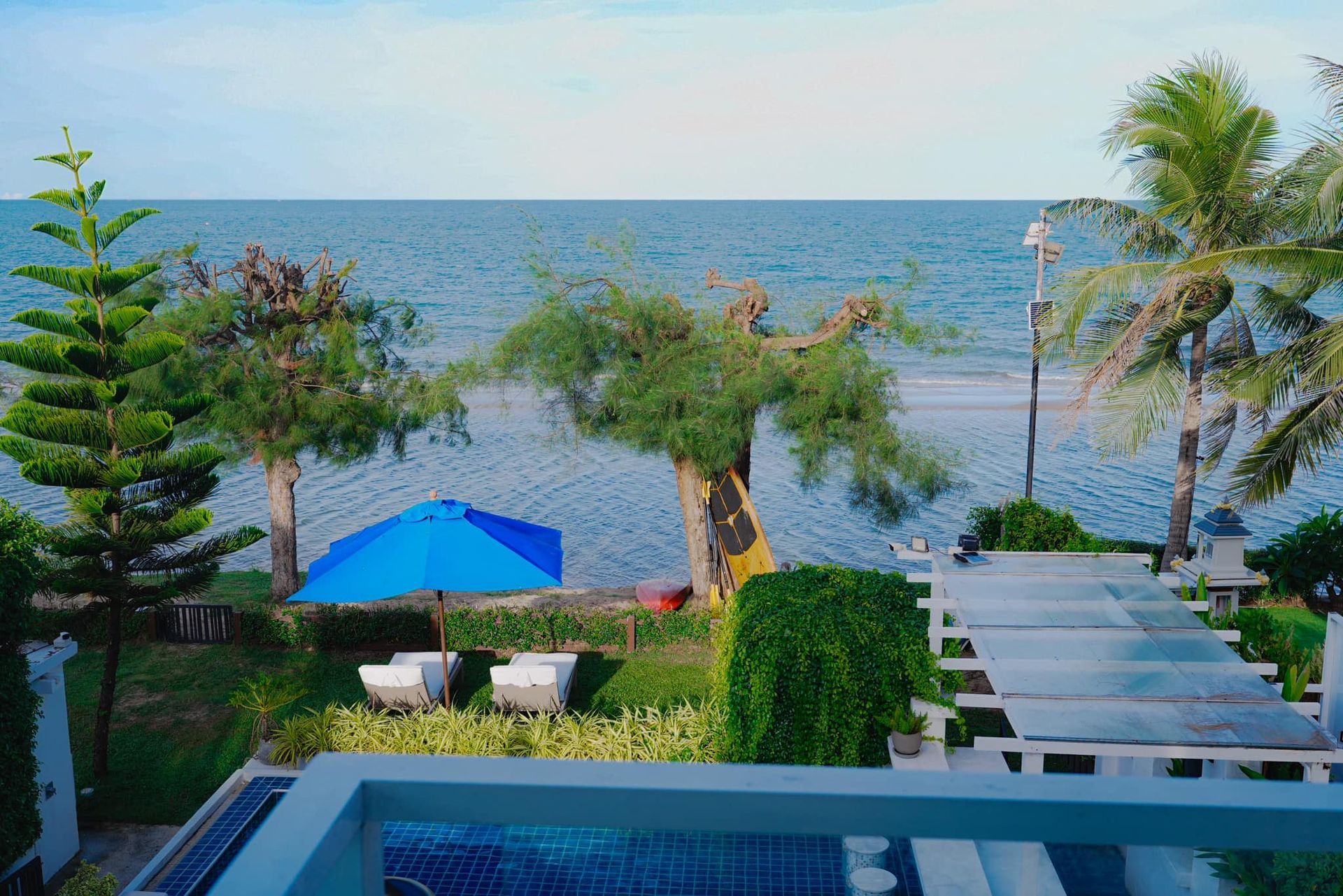 A view of the ocean from a balcony with a blue umbrella.