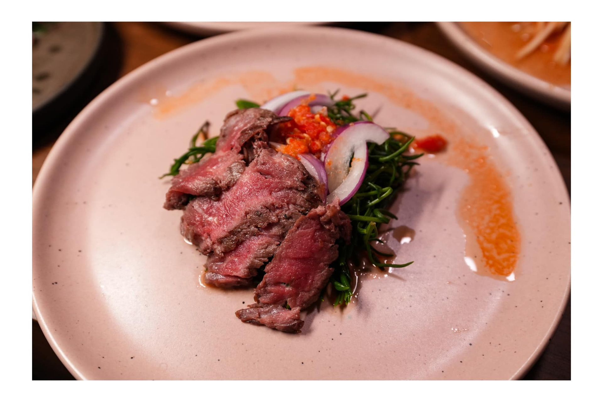 A close up of a plate of food with meat and vegetables on a table.
