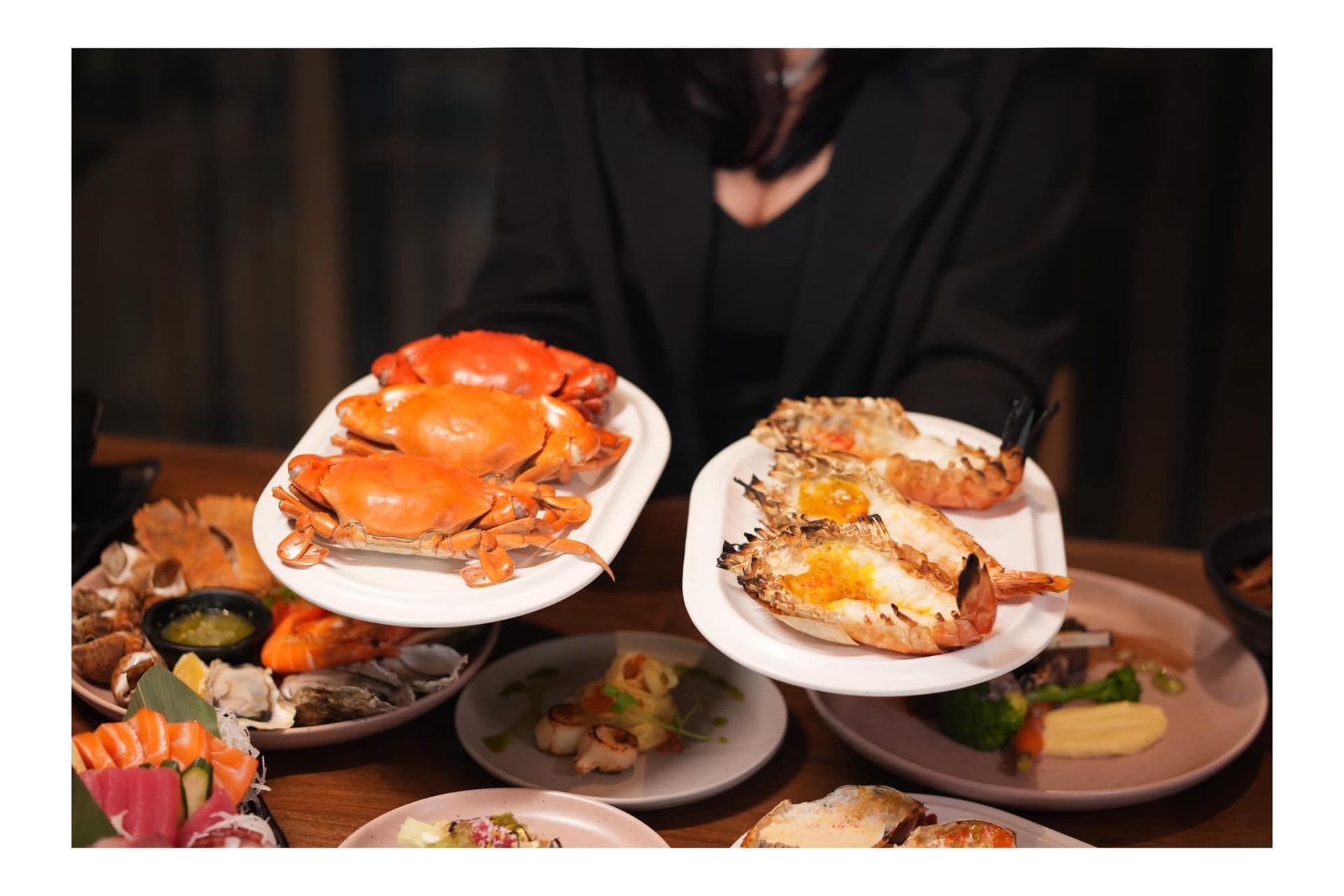 A woman is holding two plates of food on a table.