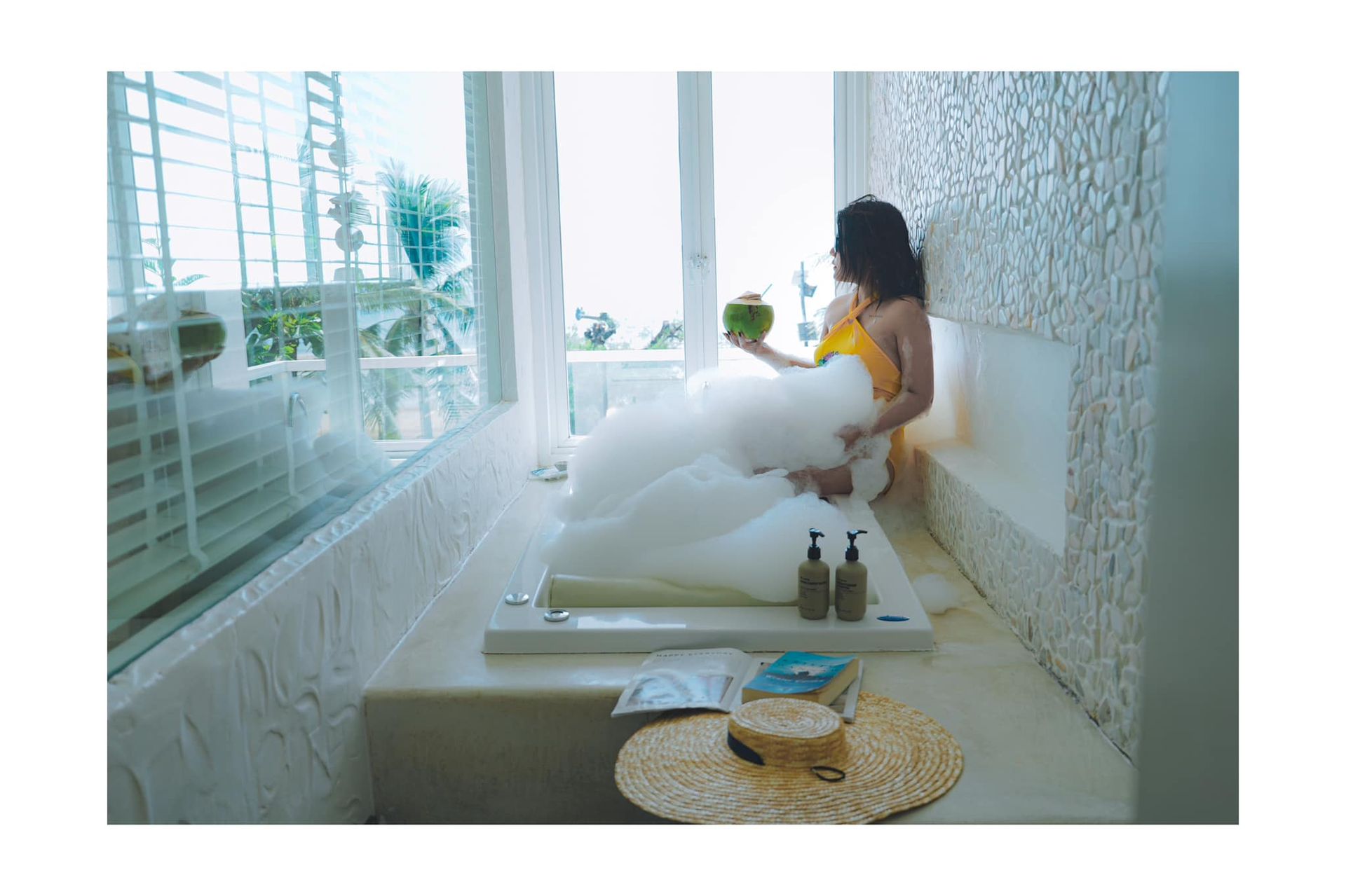 A woman is taking a bath in a bathtub while holding a coconut.