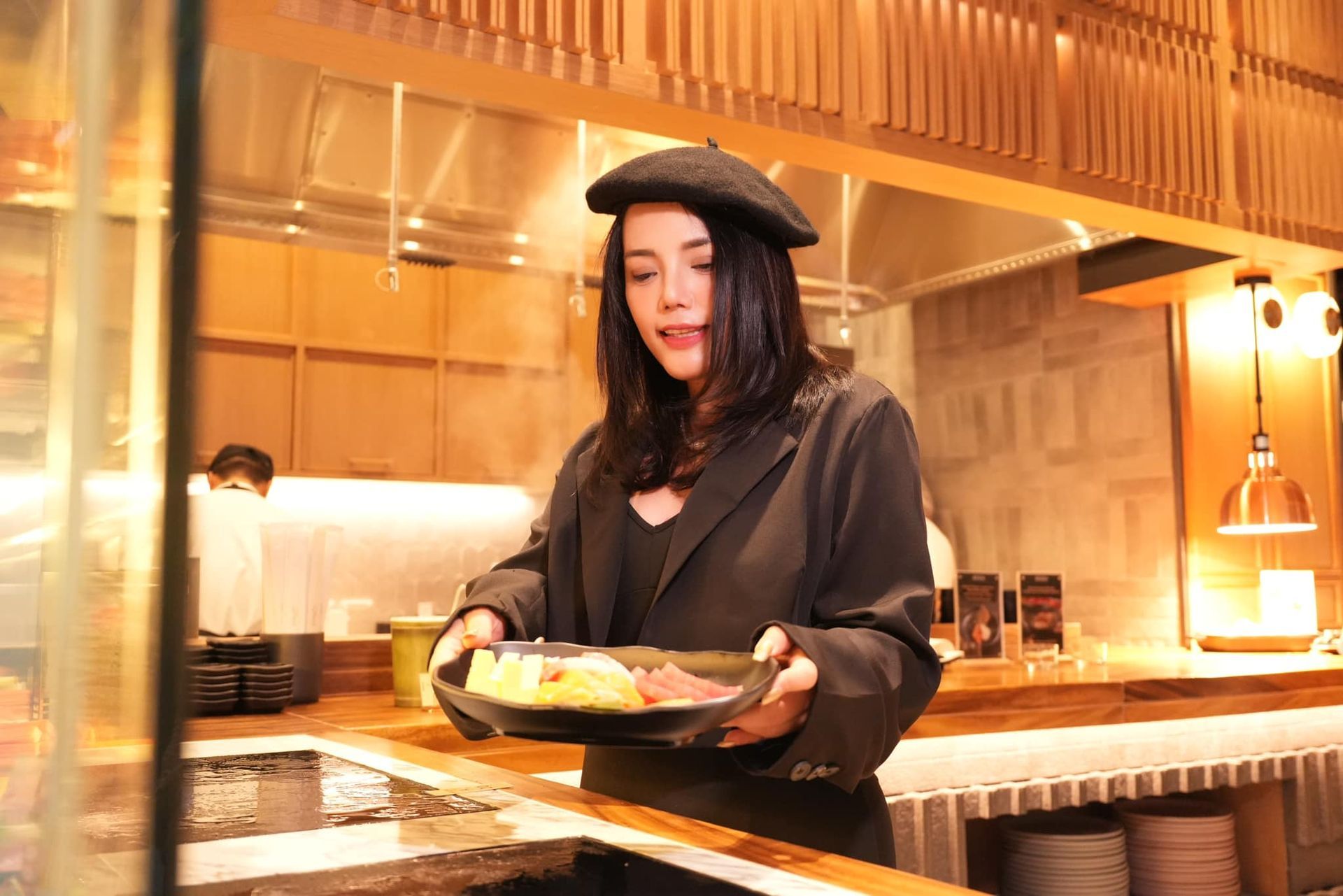 A woman in a beret is holding a plate of food in a restaurant.