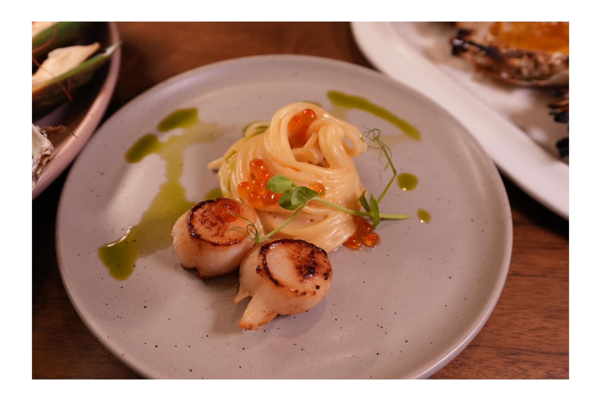 A plate of food with noodles and scallops on a table.