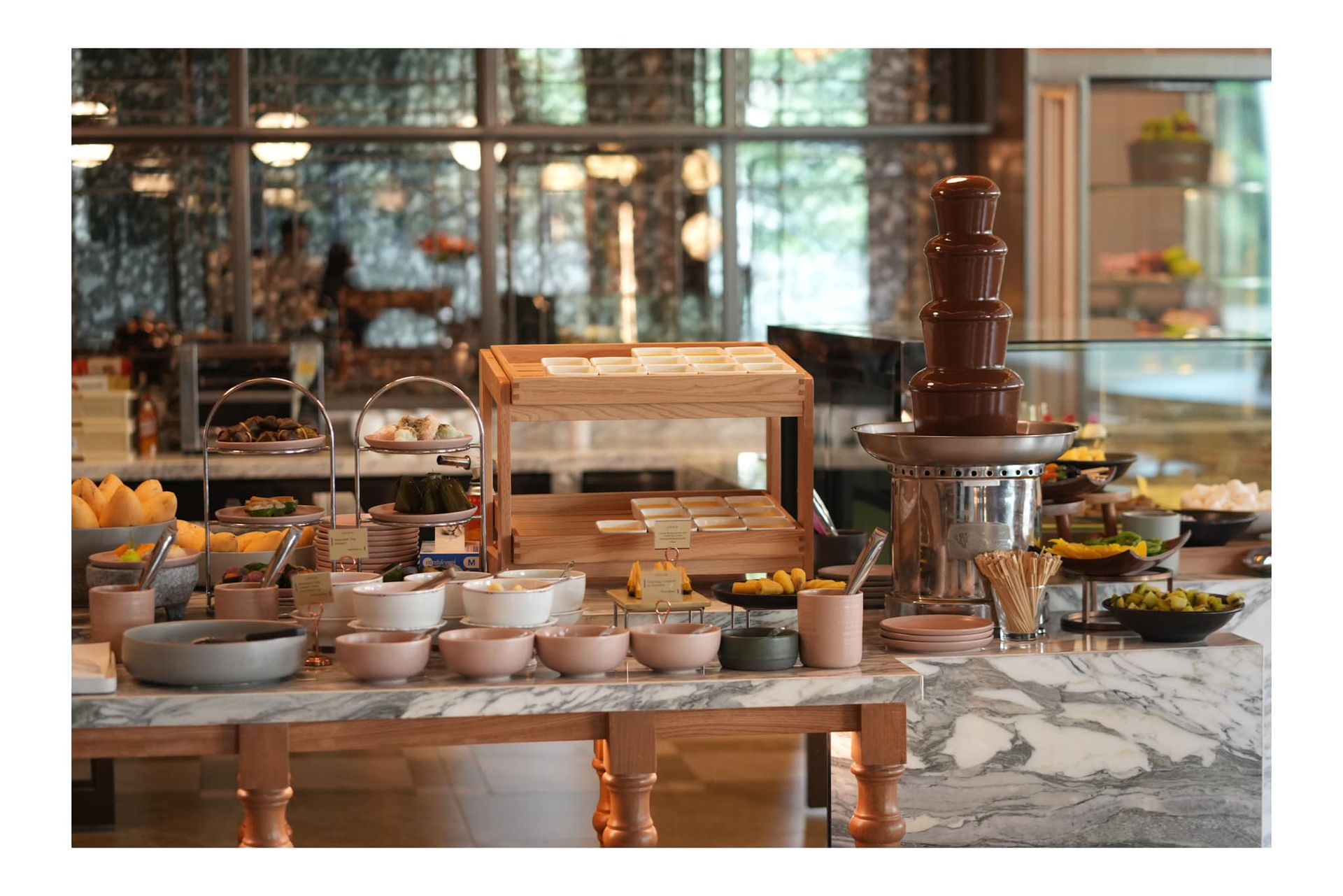 A buffet table with bowls and a chocolate fountain in a restaurant.