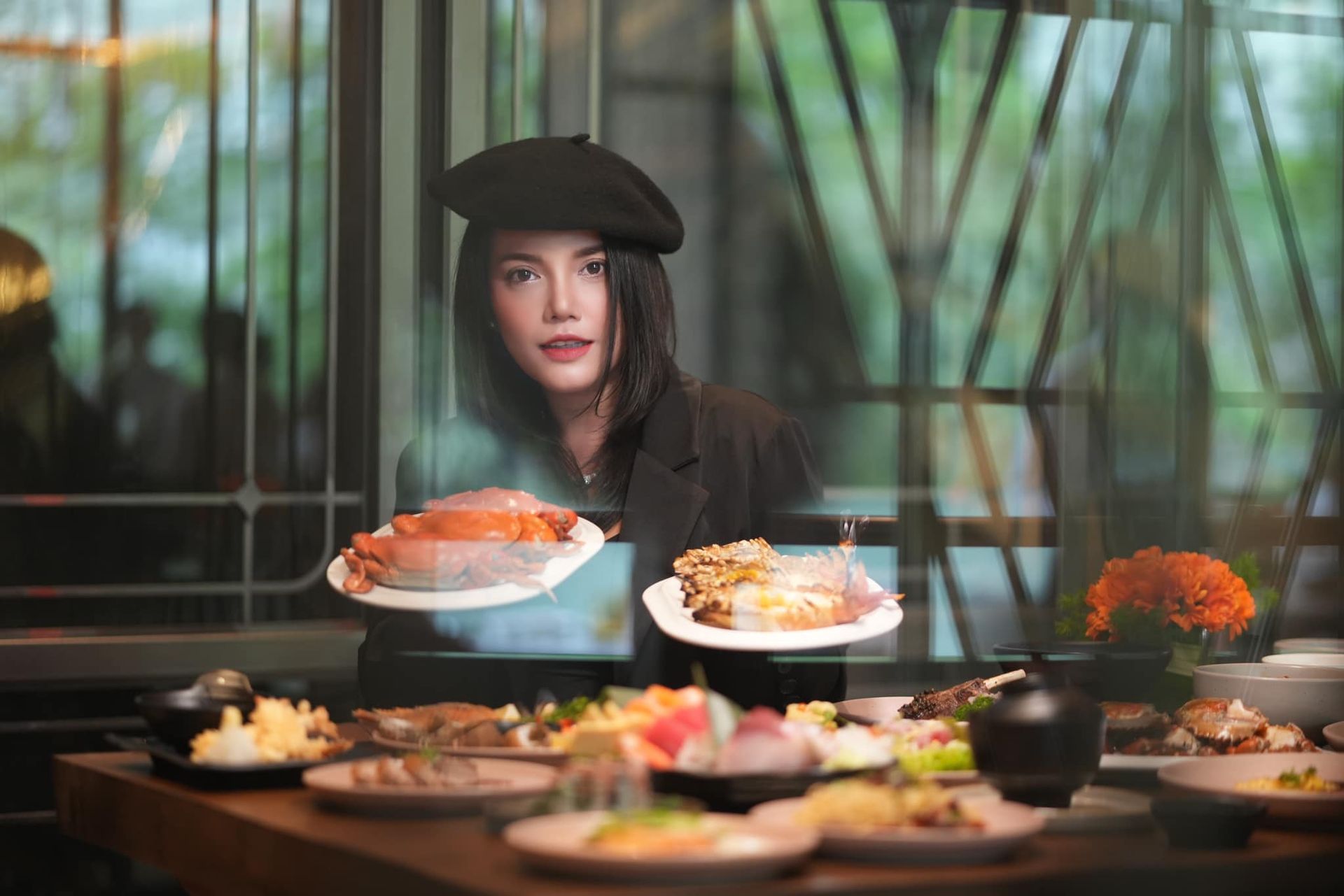 A woman is holding two plates of food in front of a table filled with food.