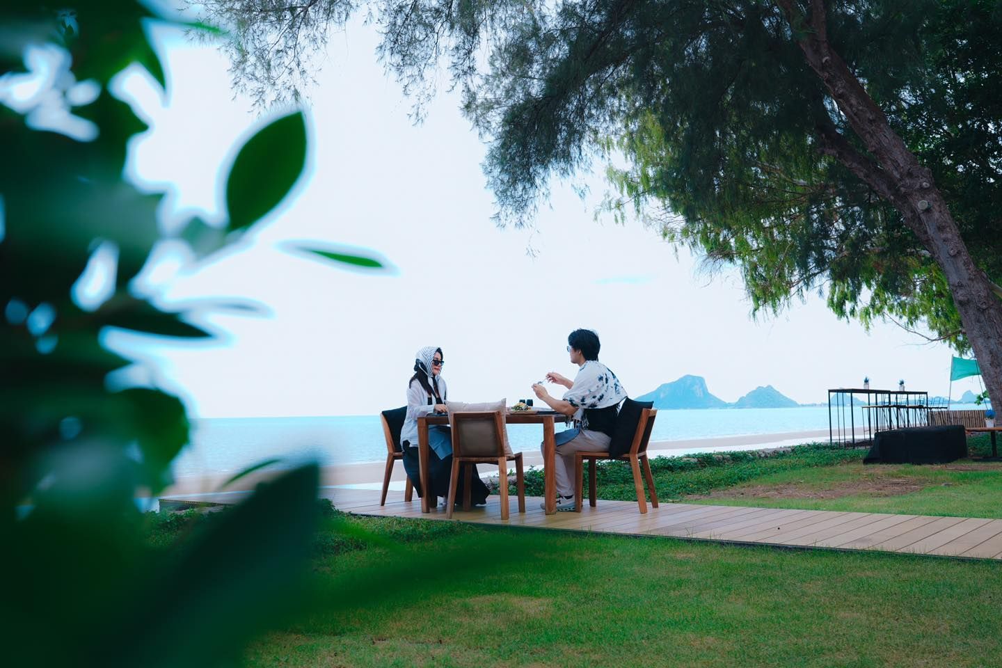 Two people are sitting at a table in front of the ocean.