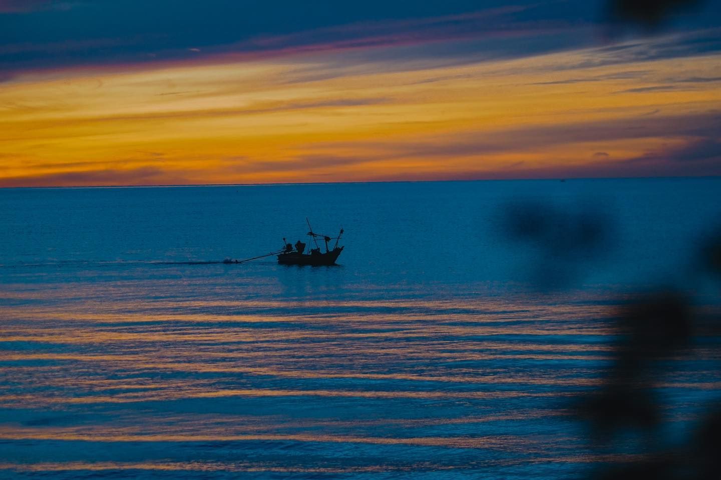 A boat is floating on top of a body of water at sunset.