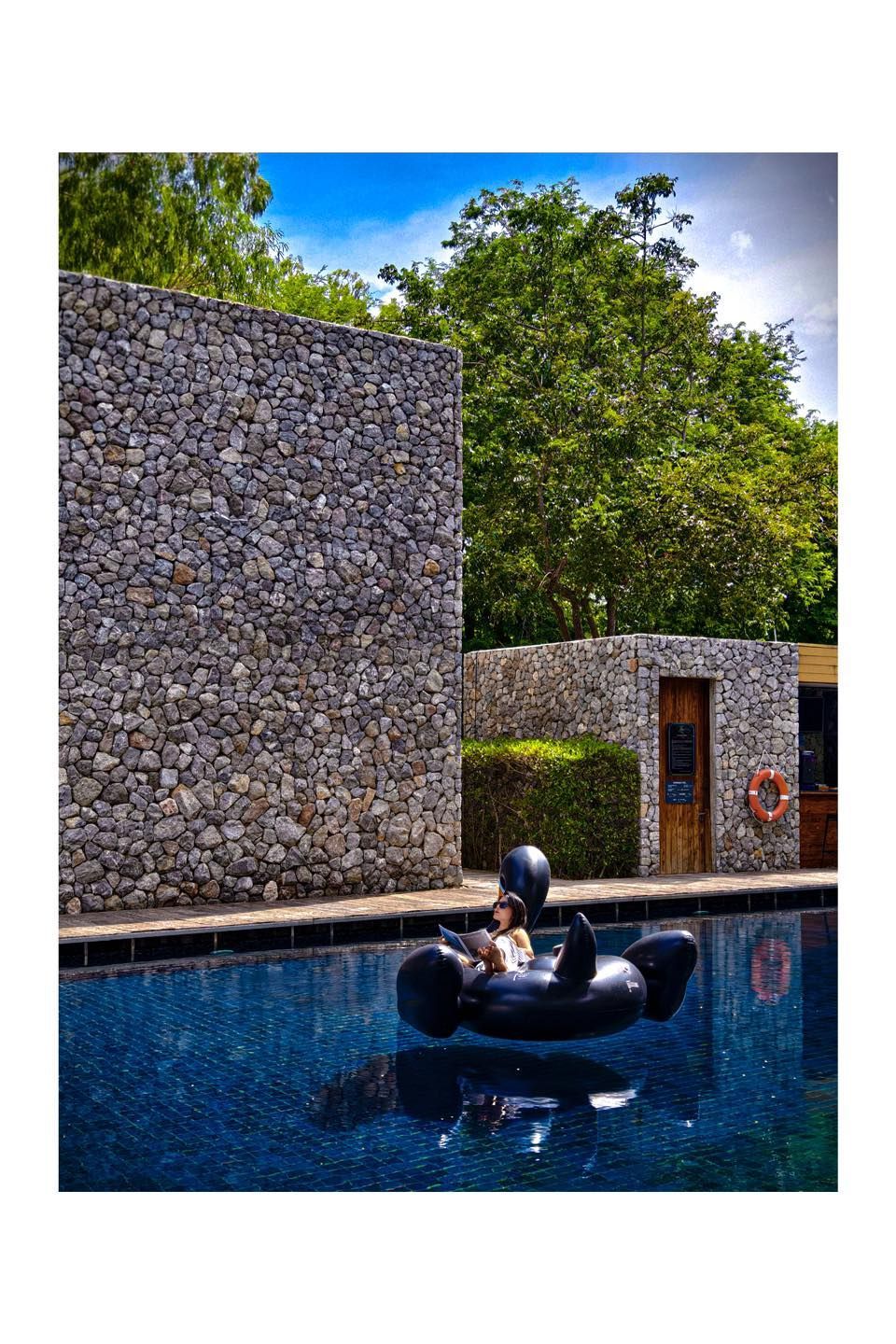 A person is floating on a raft in a swimming pool.