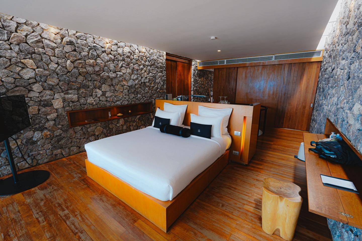 A hotel room with a large bed and a stone wall.