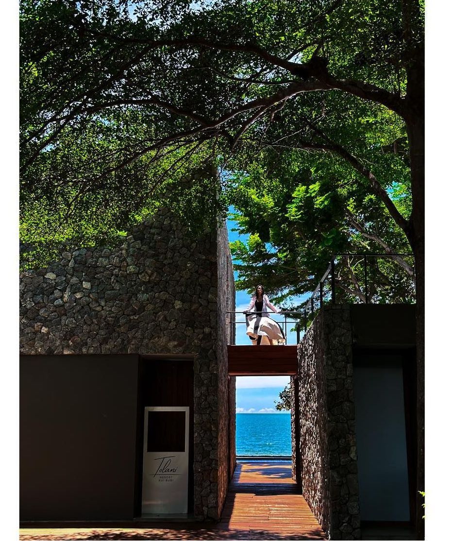 A woman standing on a balcony overlooking the ocean
