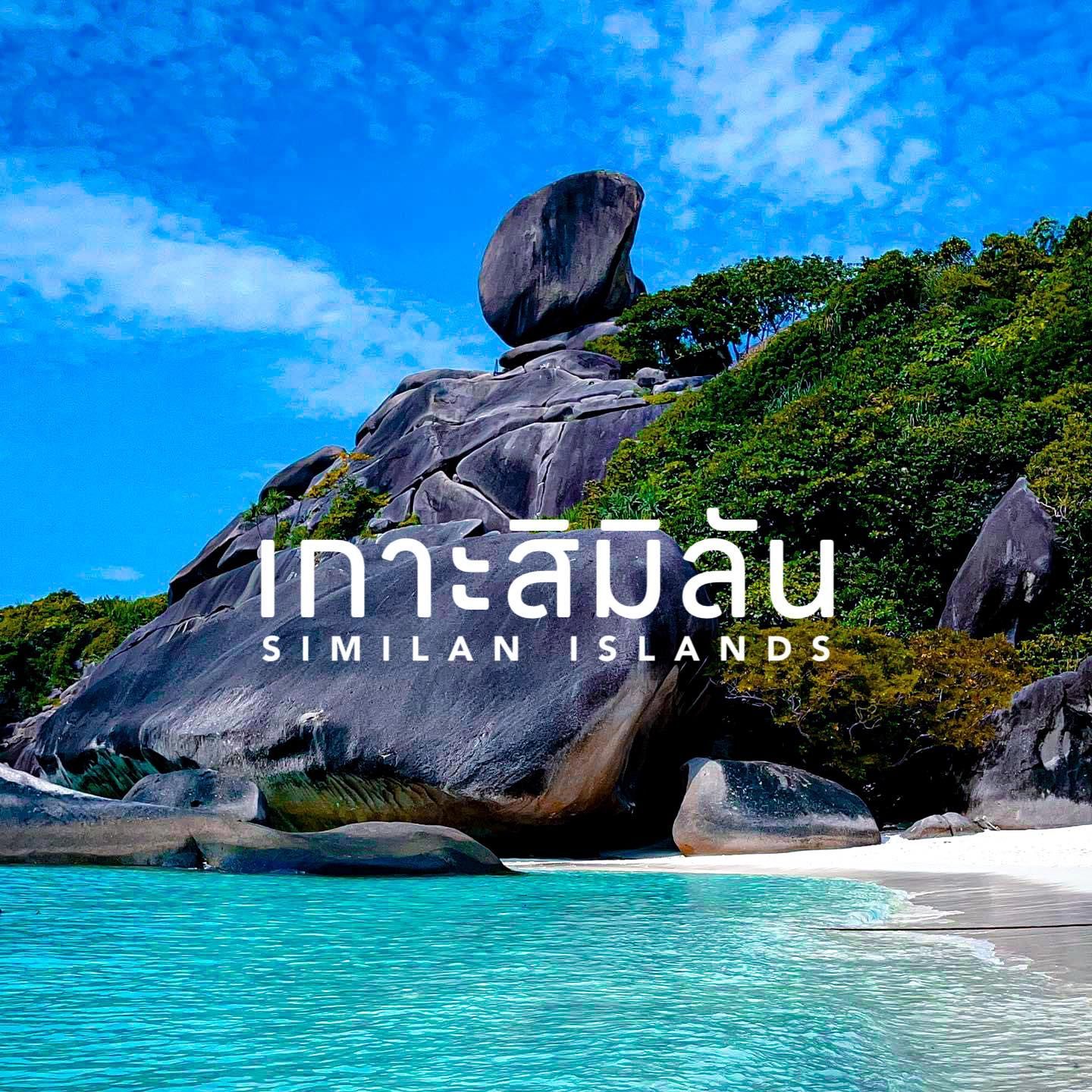 A large rock sitting on top of a beach next to a body of water in Similan Islands.
