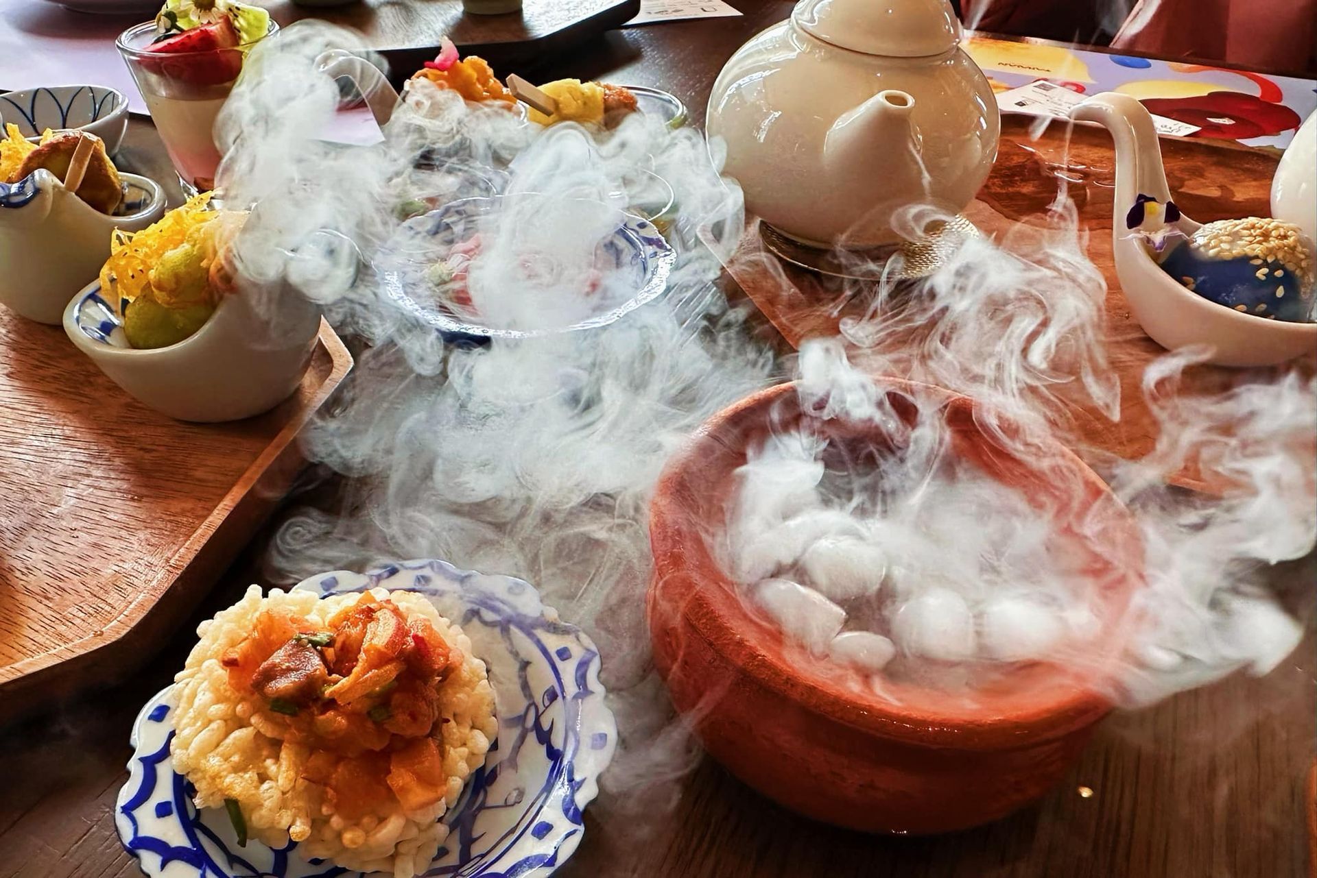 A table topped with plates of food and a teapot with smoke coming out of it.