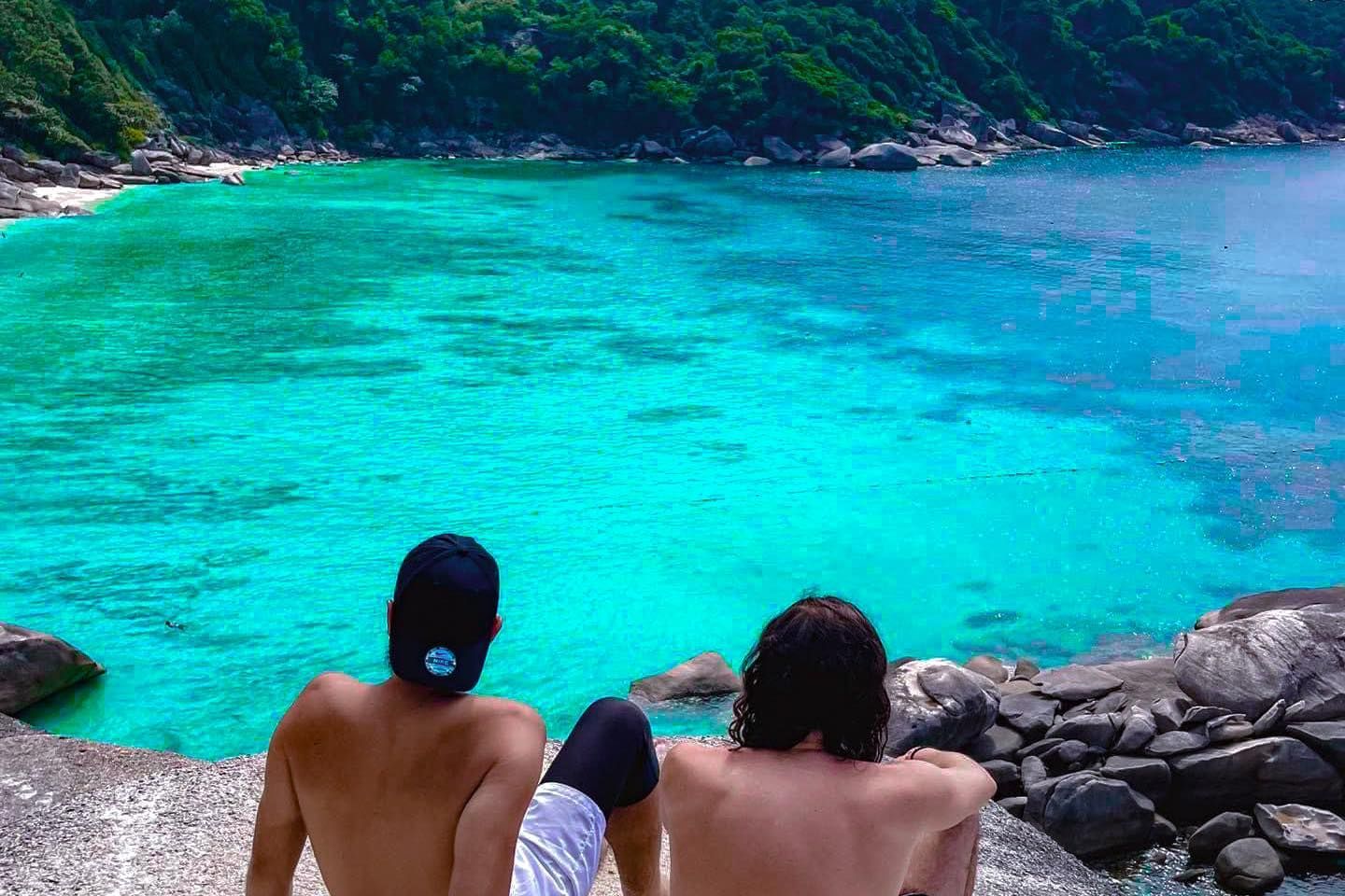 Two people are sitting on the beach looking at the ocean in the area of similan islands..