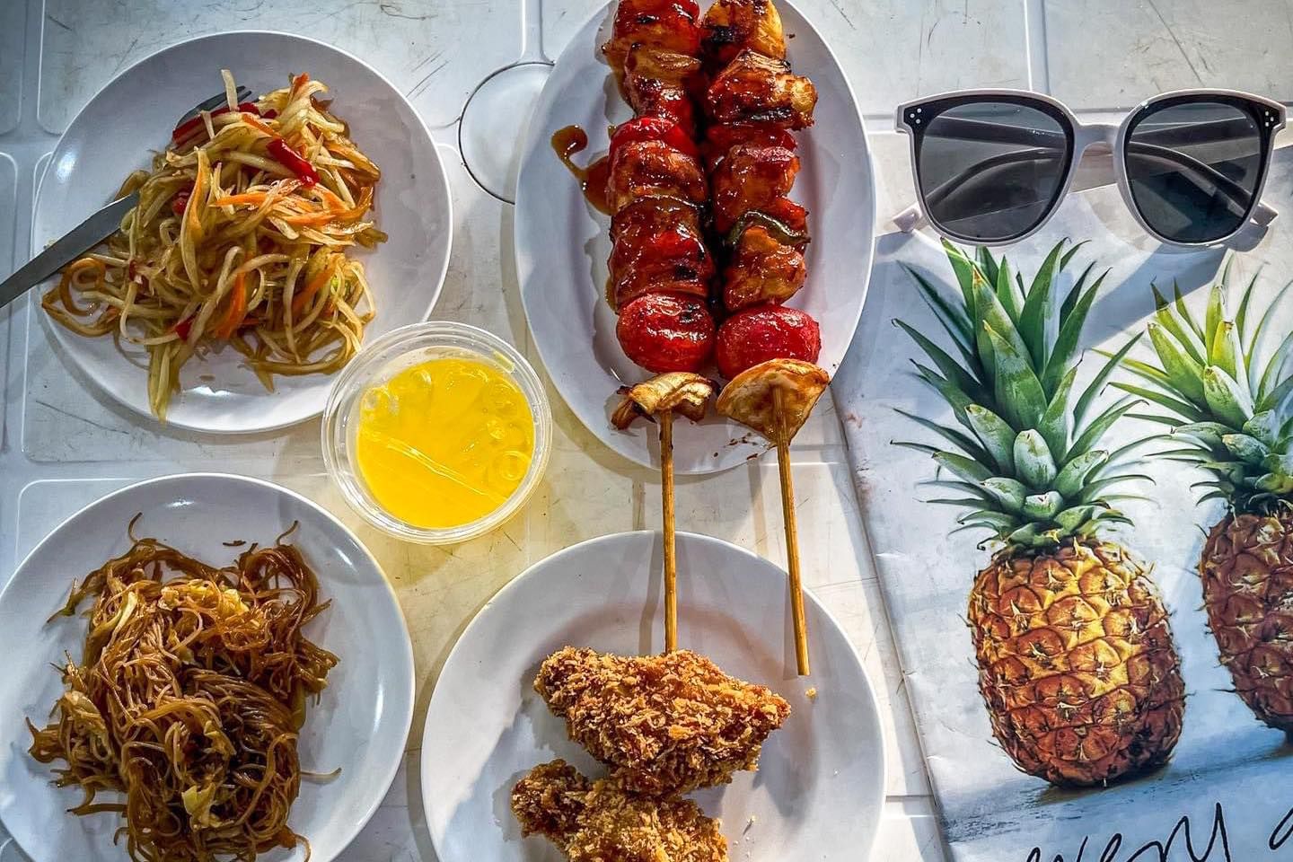 A table topped with plates of food and pineapples.