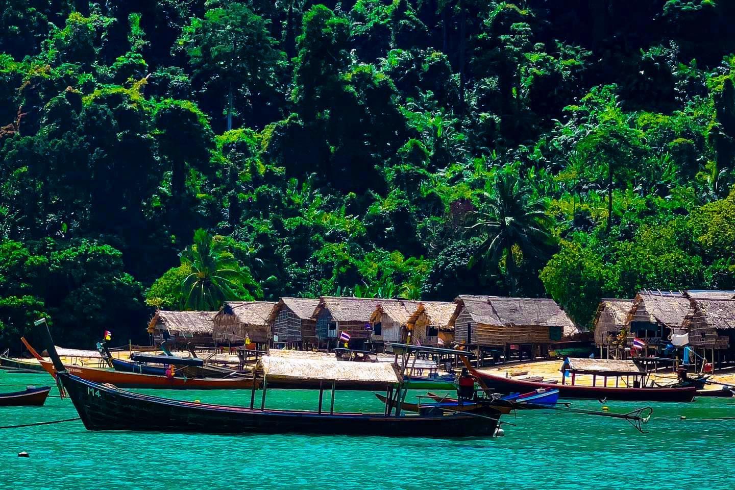 A boat is floating in the water near a small village