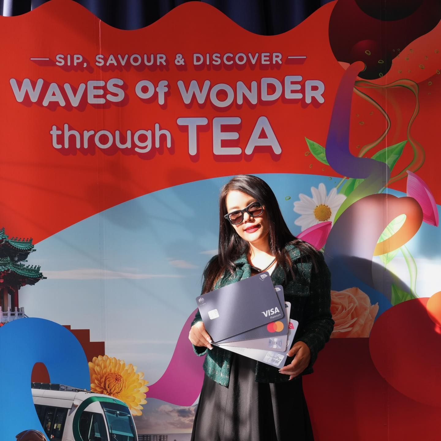 A woman stands in front of a sign that says waves of wonder through tea in Taiwan