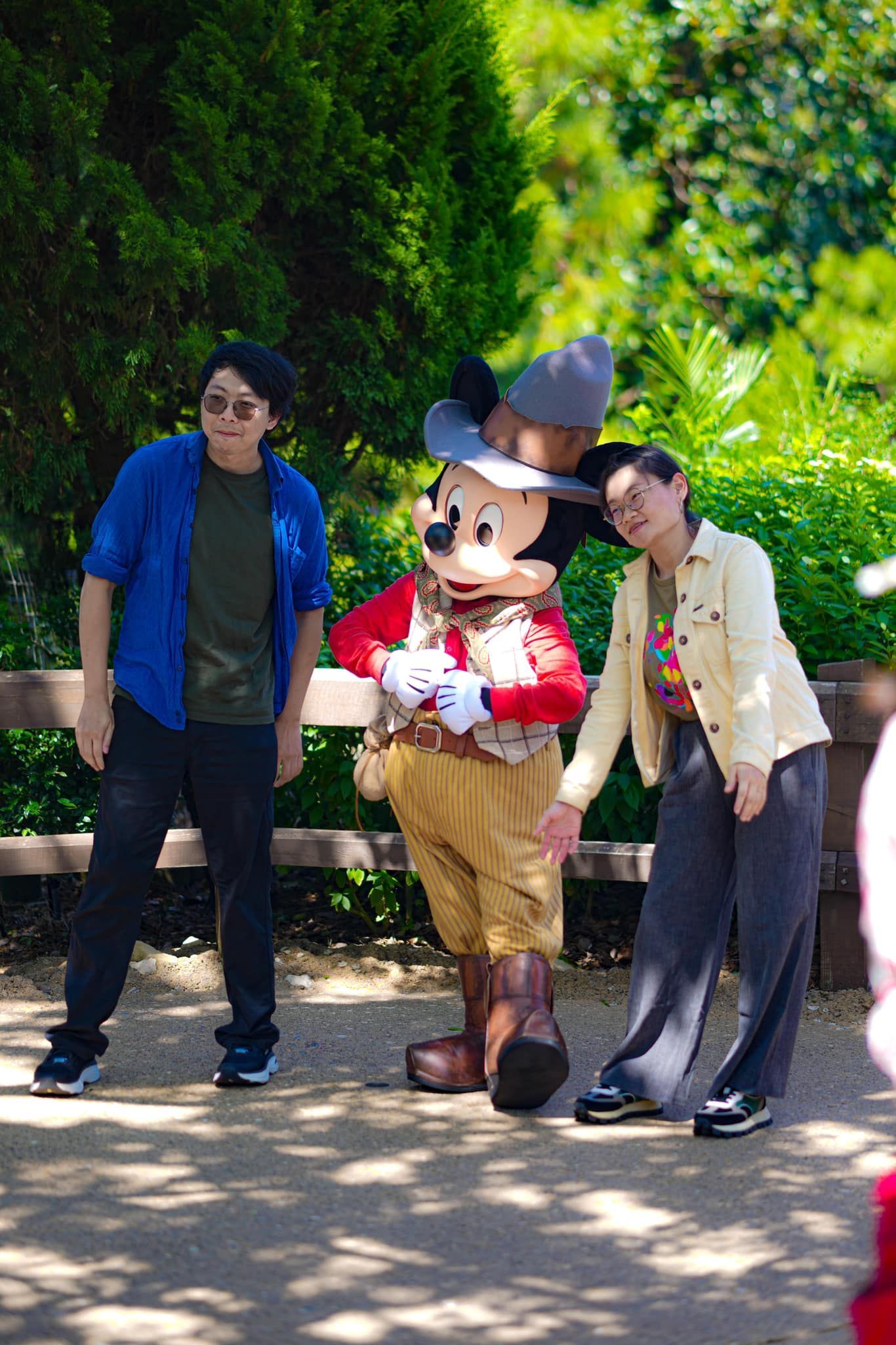 A man and a woman are standing next to a mickey mouse mascot.