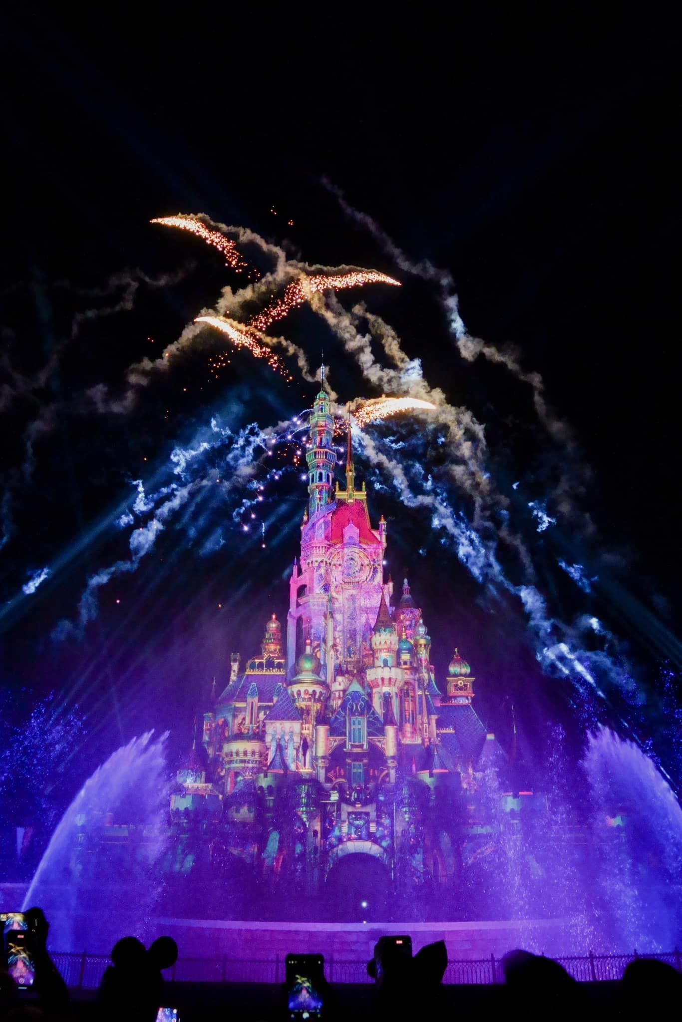 A Disney castle is projected on a wall with fireworks in the background.