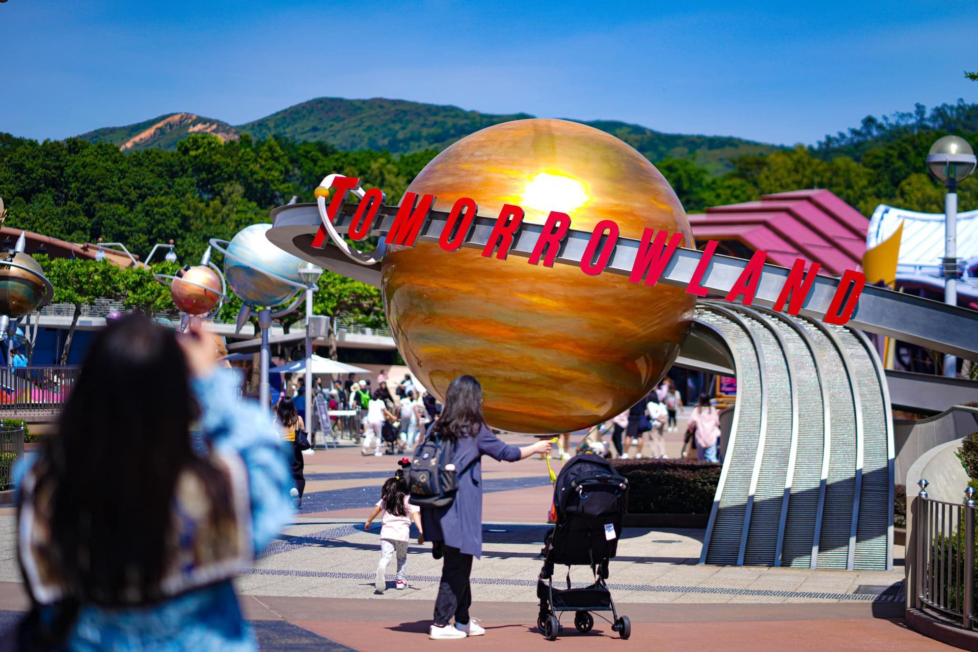 A woman is taking a picture of a giant globe at a theme park.