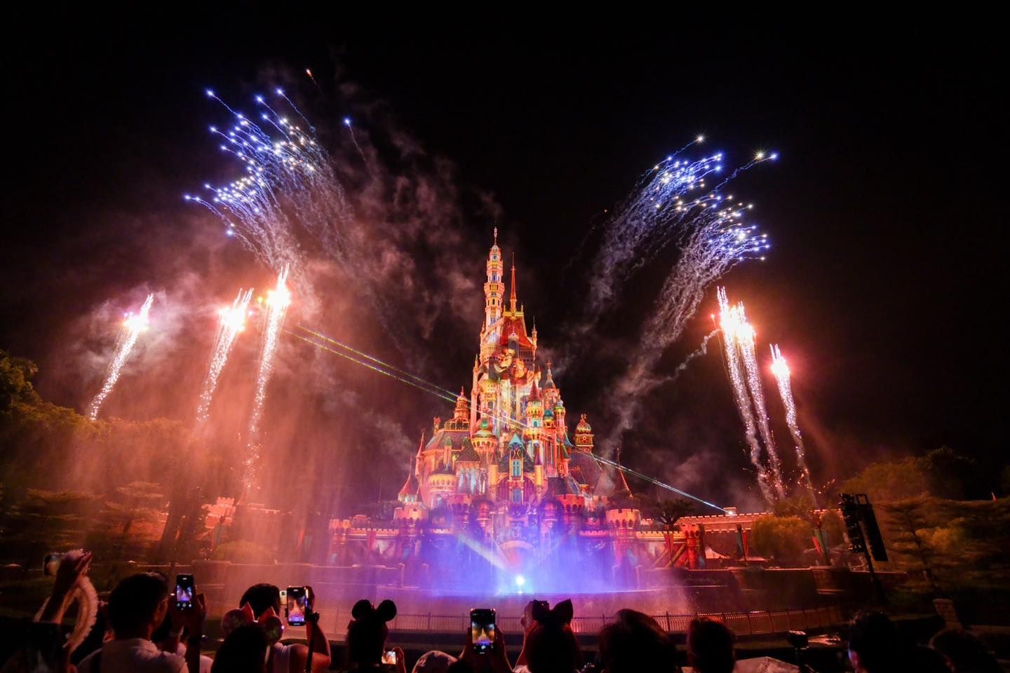 A group of people are watching fireworks over a castle.