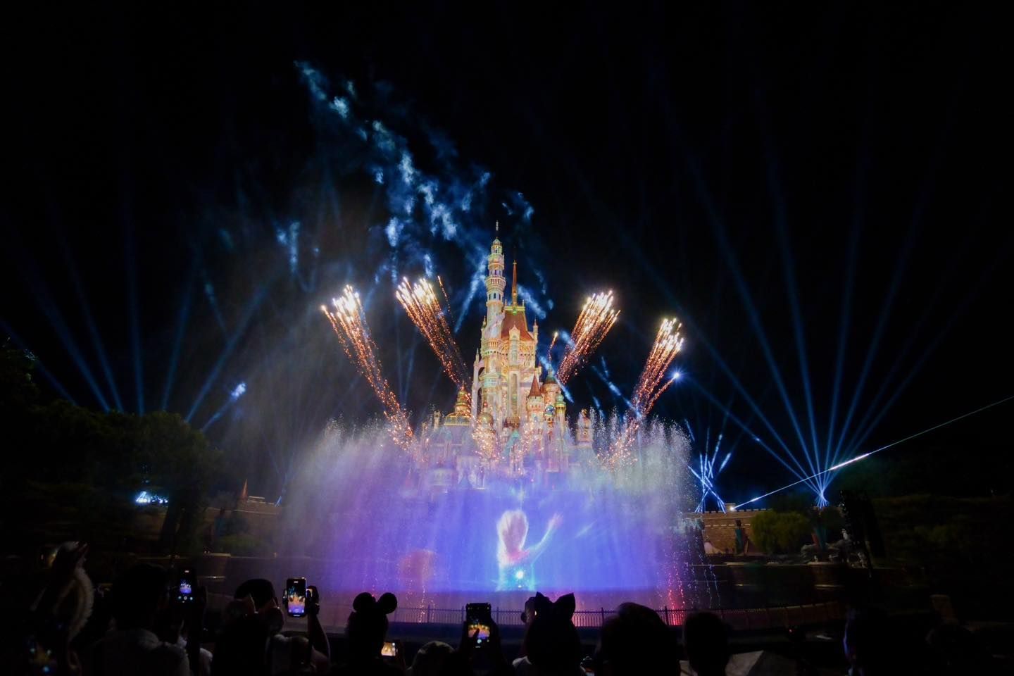 A crowd of people are watching a fireworks display in front of a castle.