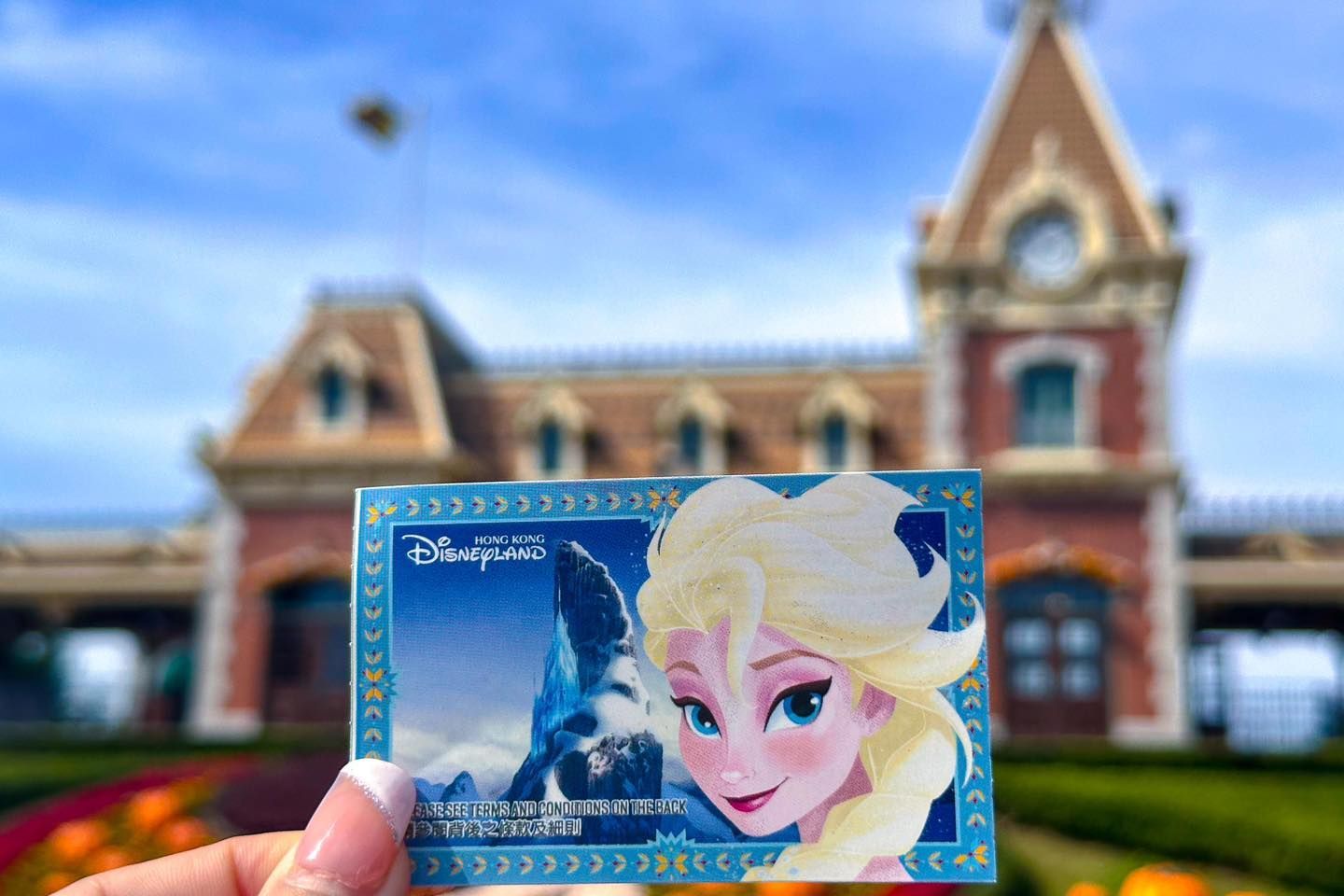 A person is holding a frozen ticket in front of a building.