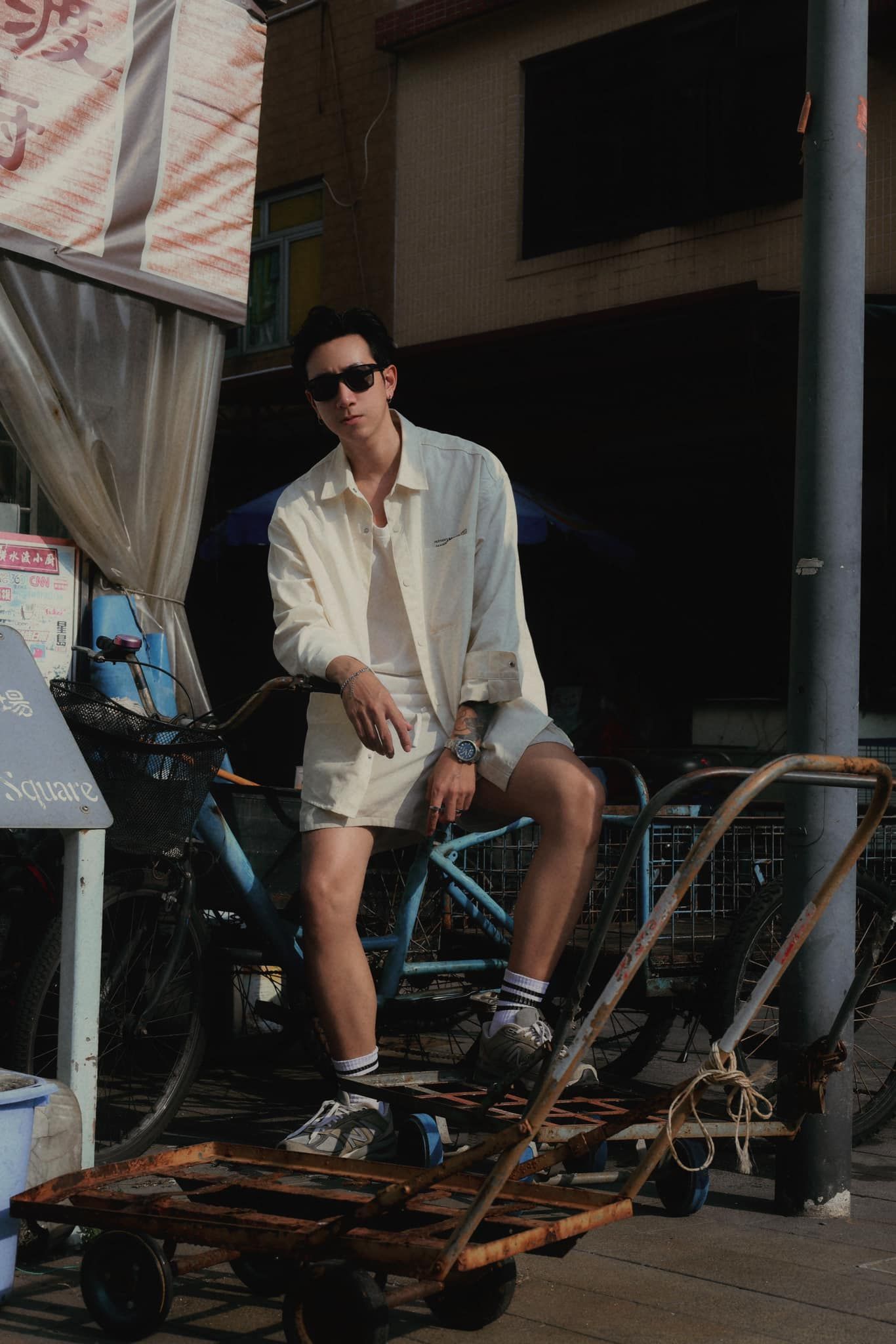 A man is sitting on a cart next to a bicycle.