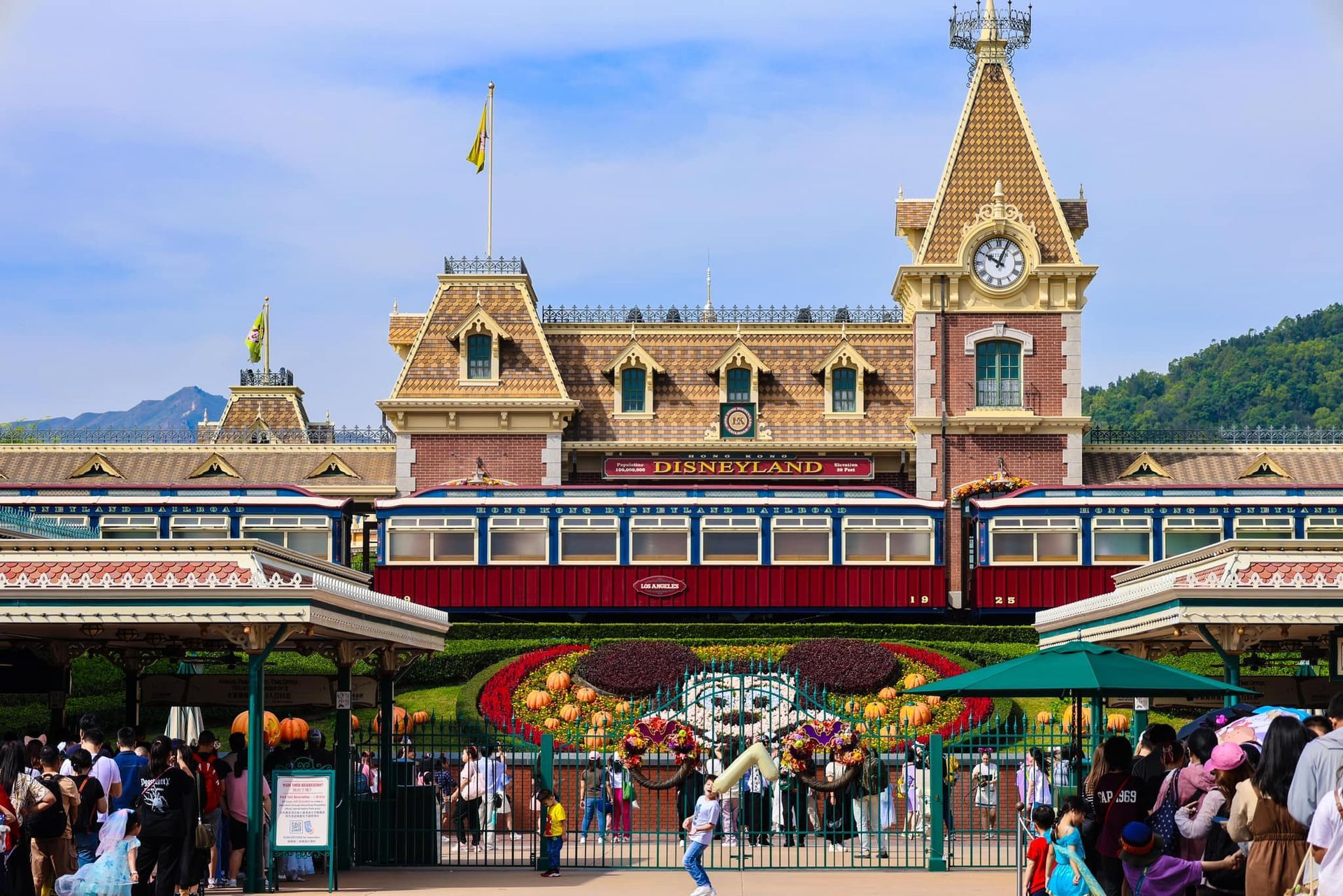 A group of people are standing in front of a disneyland train station.