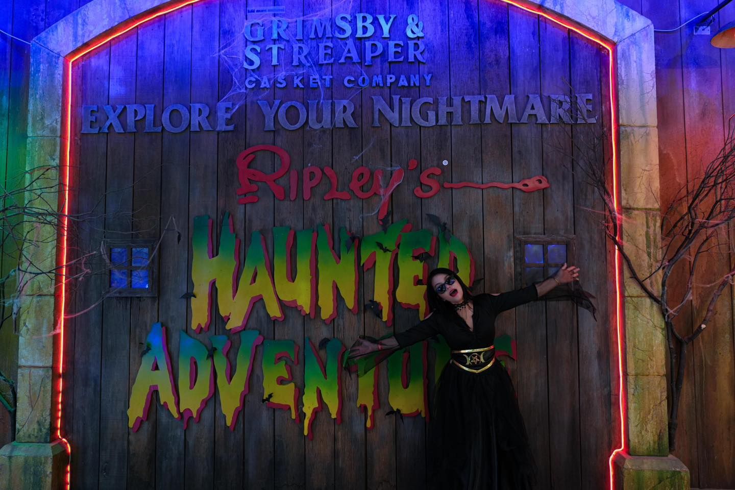 A woman is standing in front of a haunted adventure sign in 