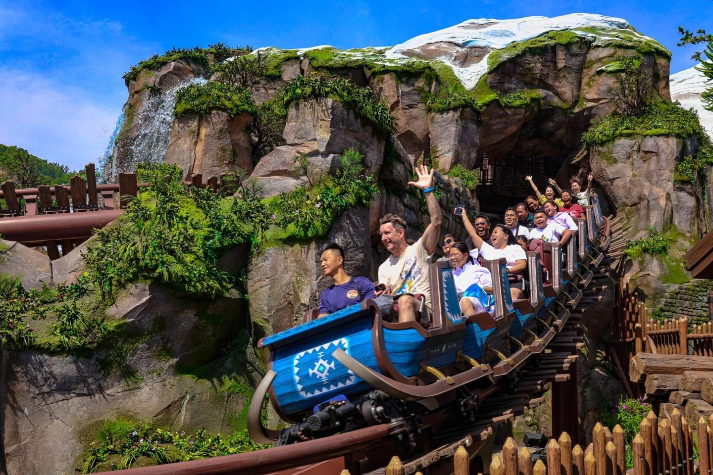 A group of people are riding a roller coaster in a theme park.