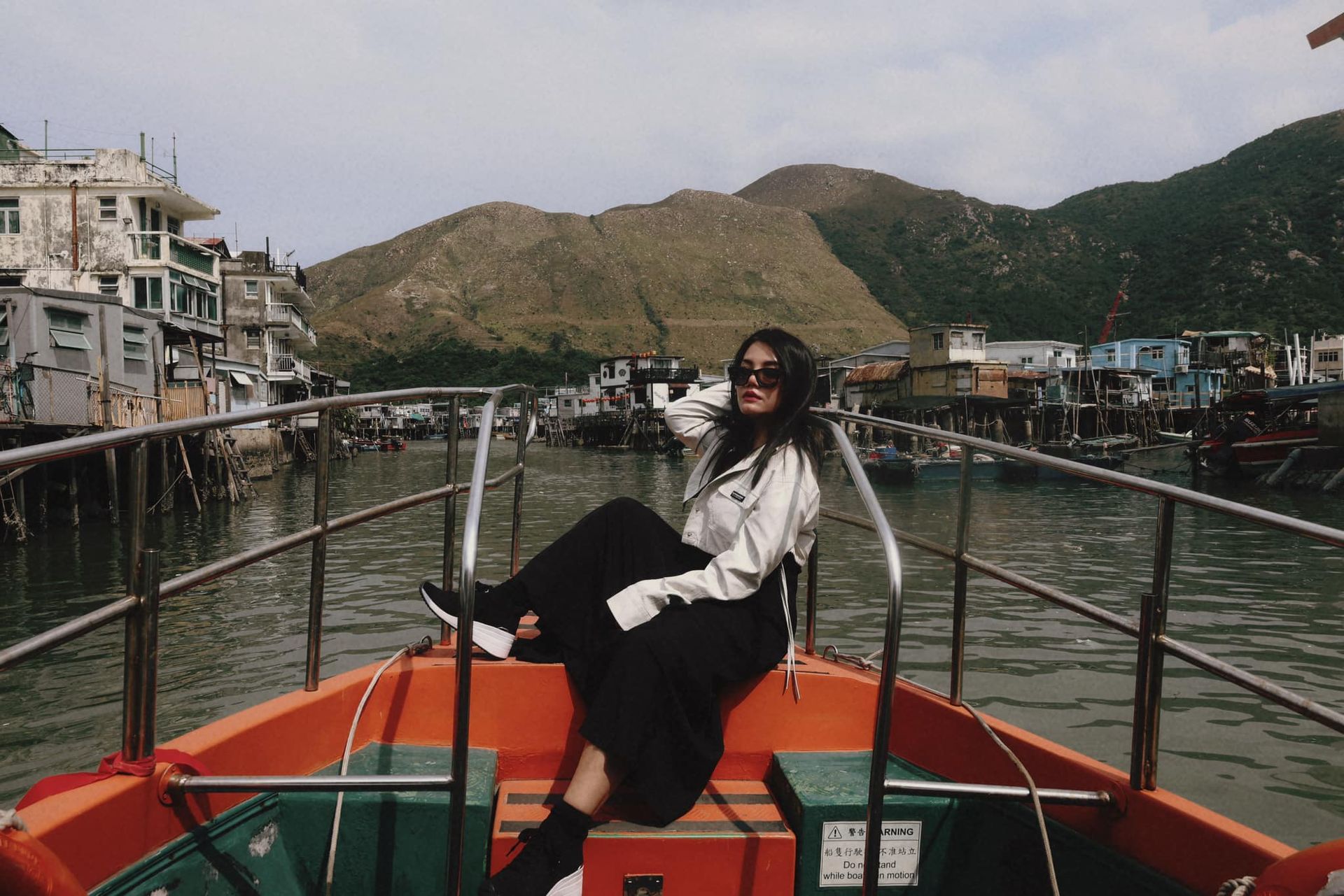 A woman is sitting on the back of a boat in the water.
