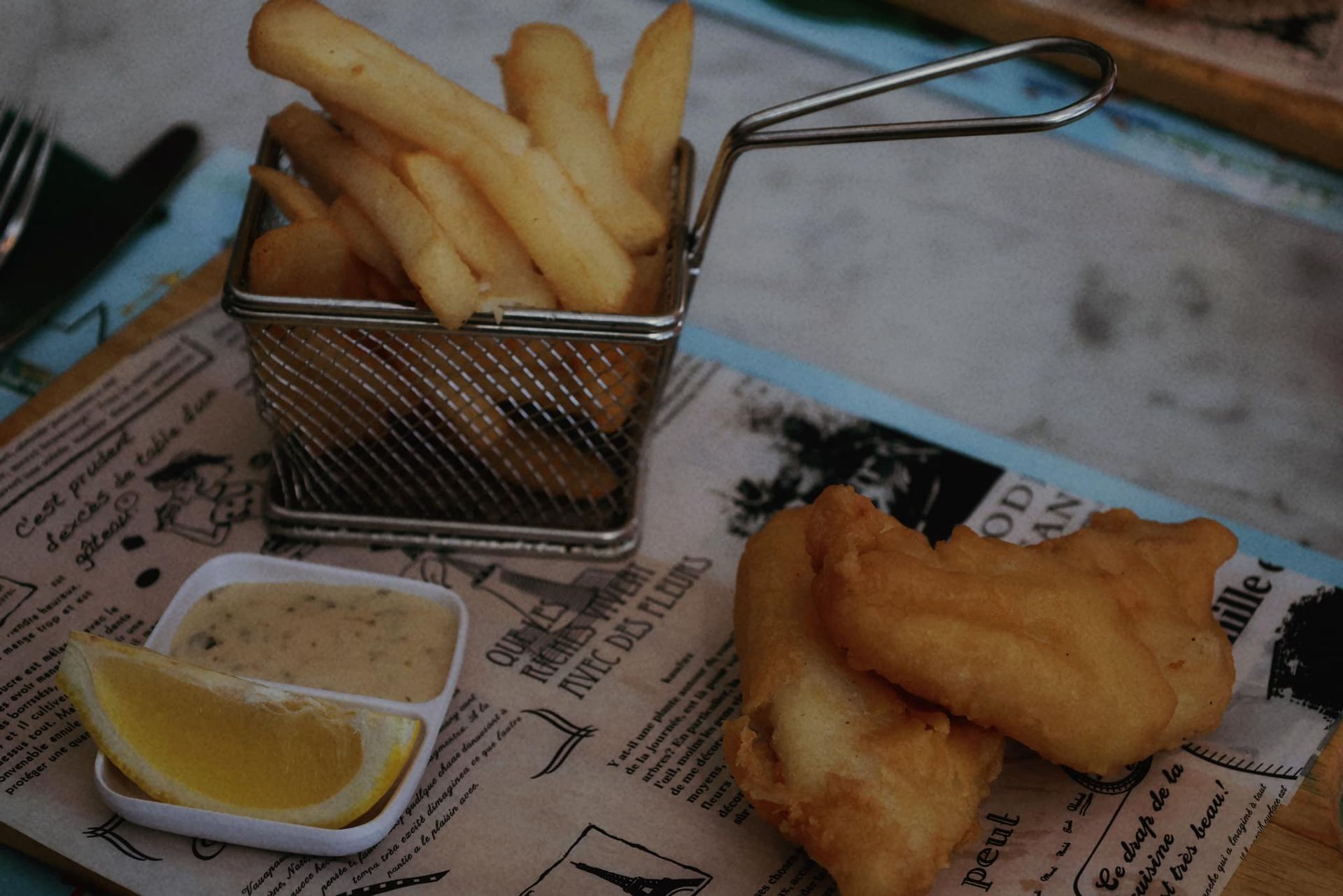 A basket of french fries next to a basket of fish and chips