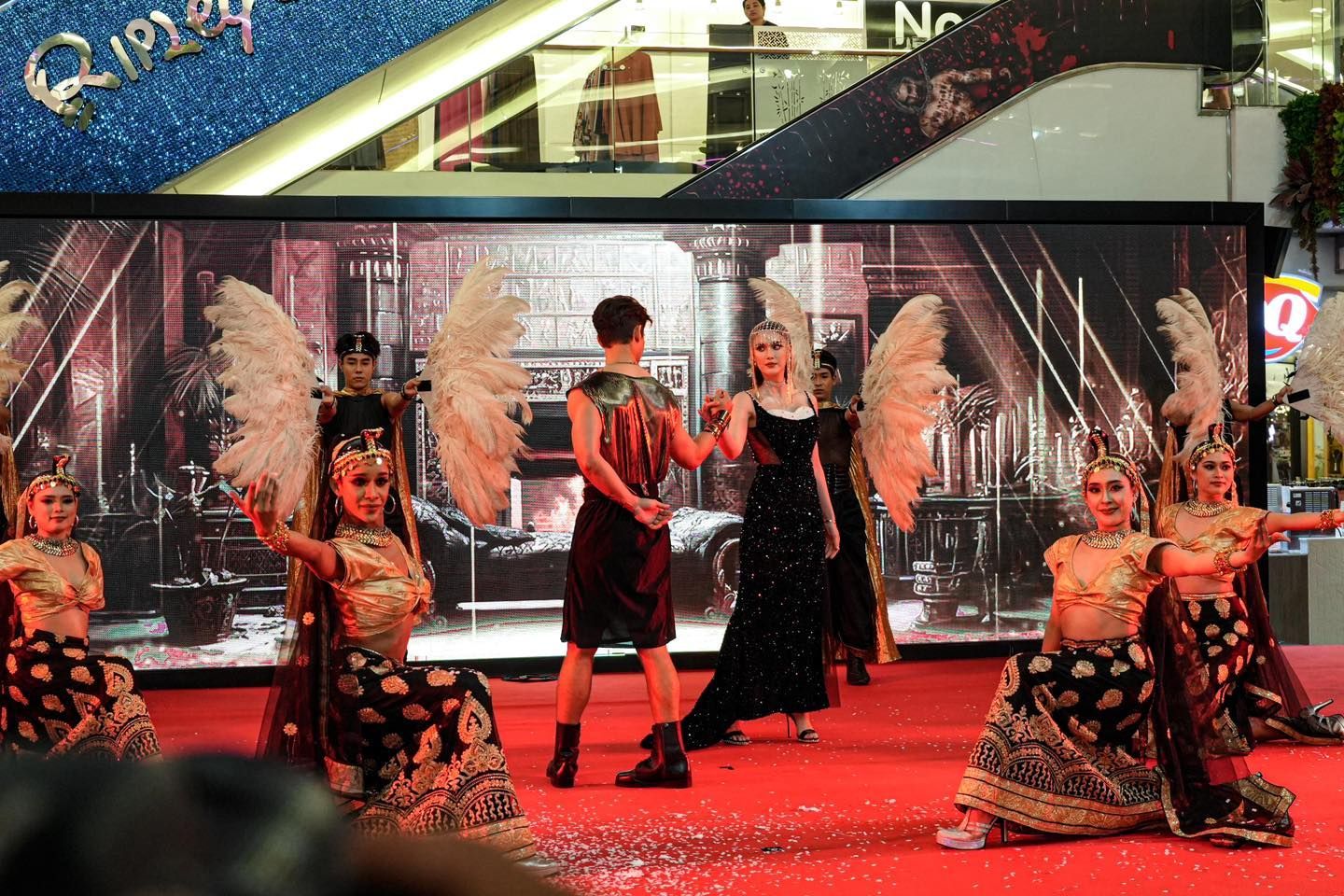 A group of people are dancing on a stage in a mall.