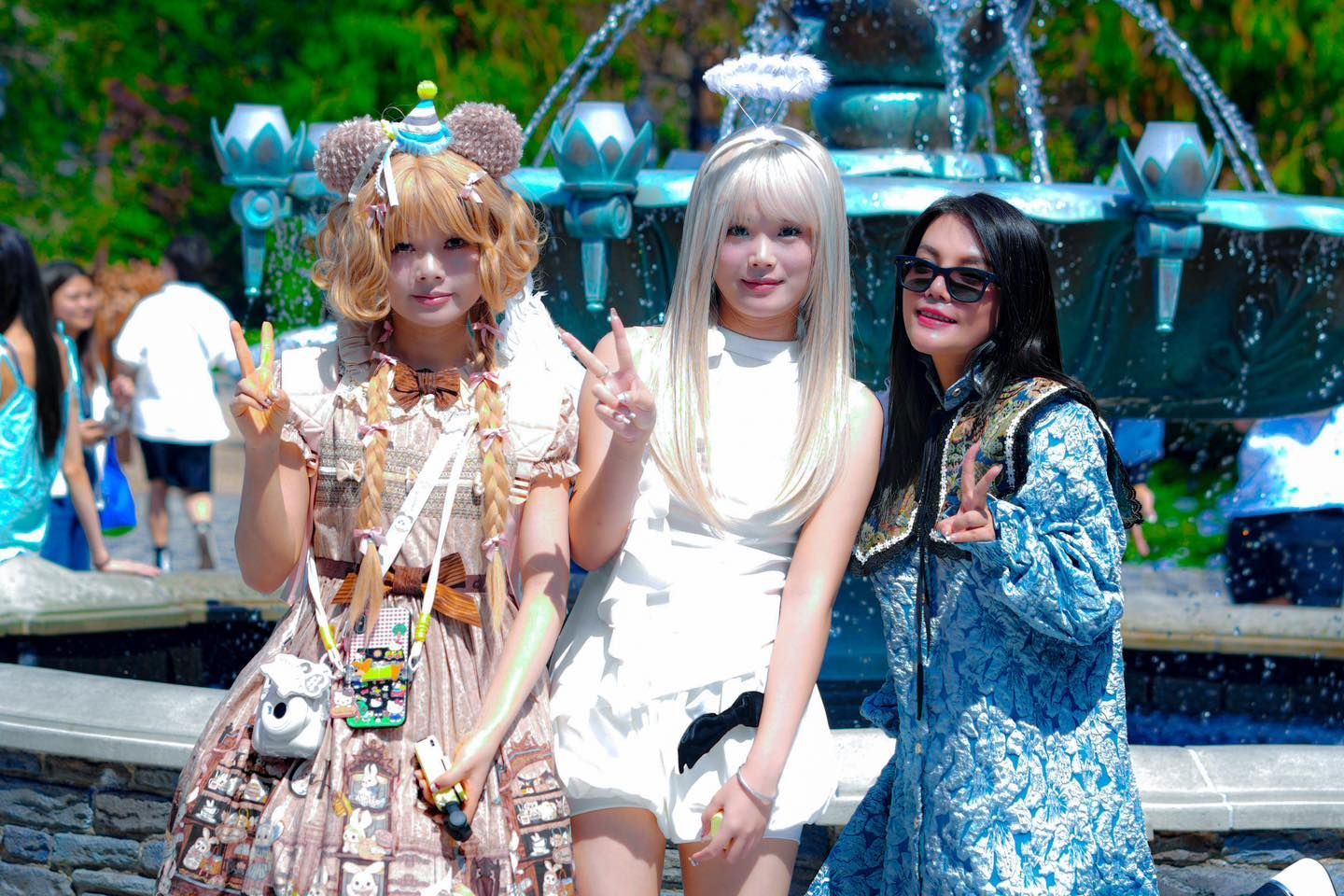 Three women are posing for a picture in front of a fountain.