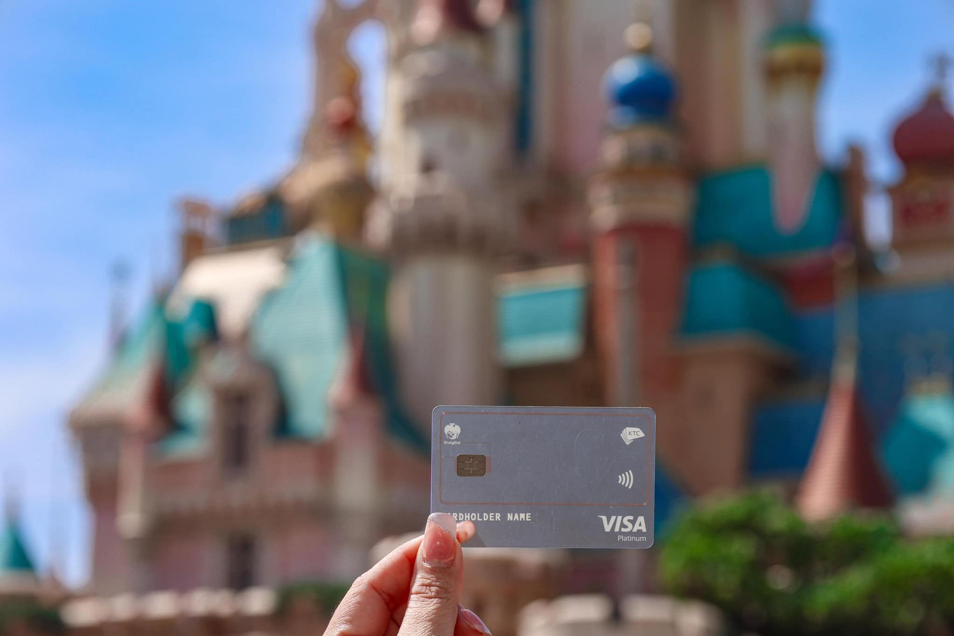 A person is holding a KTC credit card in front of a castle.